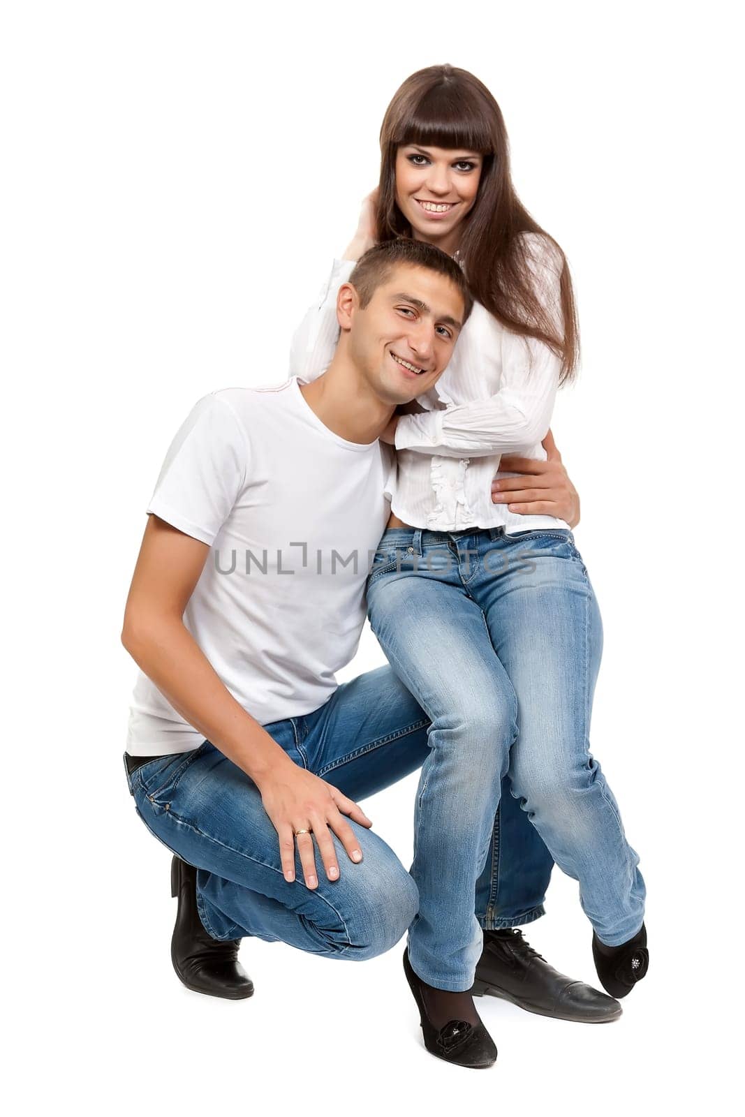 beautiful young couple sitting on the floor abd smiling isolated on a white background