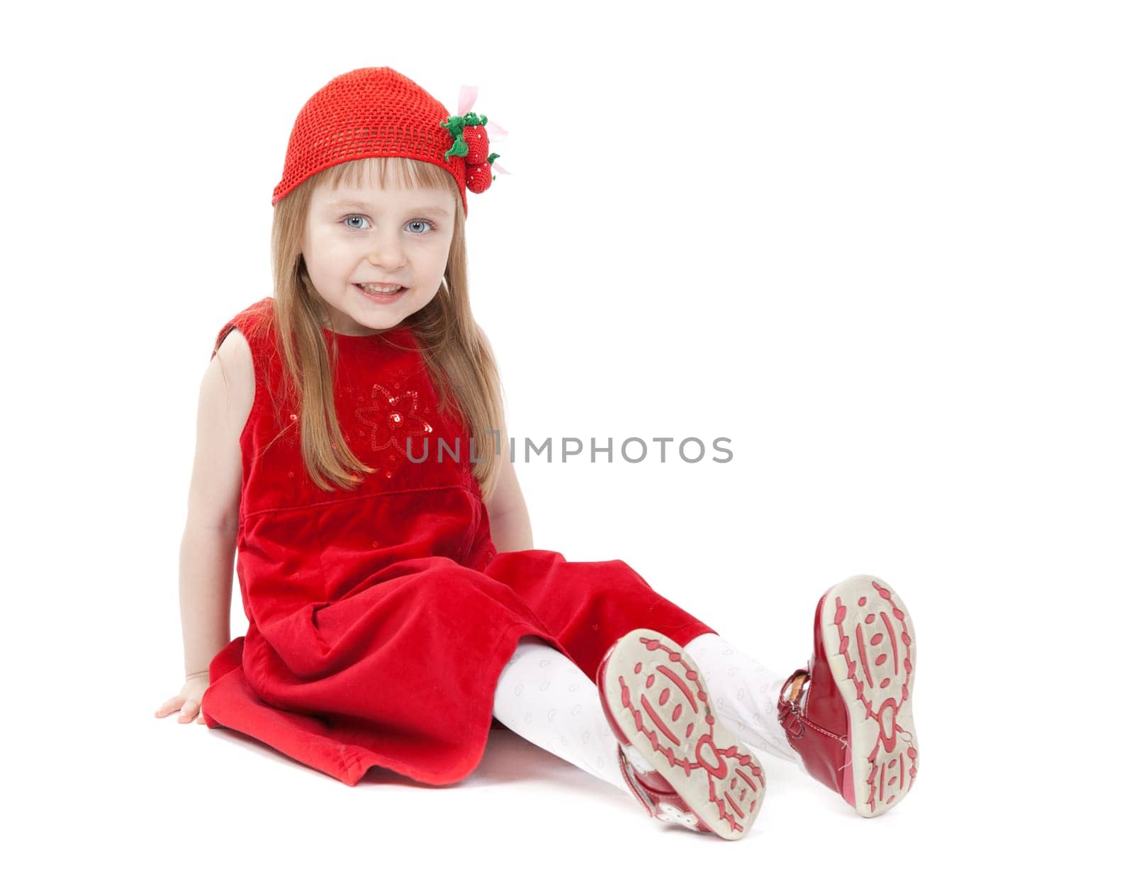 Cute little girl in a red dress sitting on the floor. Isolate on white.