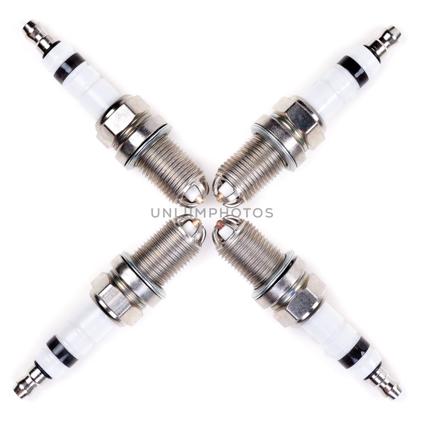 Set of four spark plugs arranged in a cross on a white background
