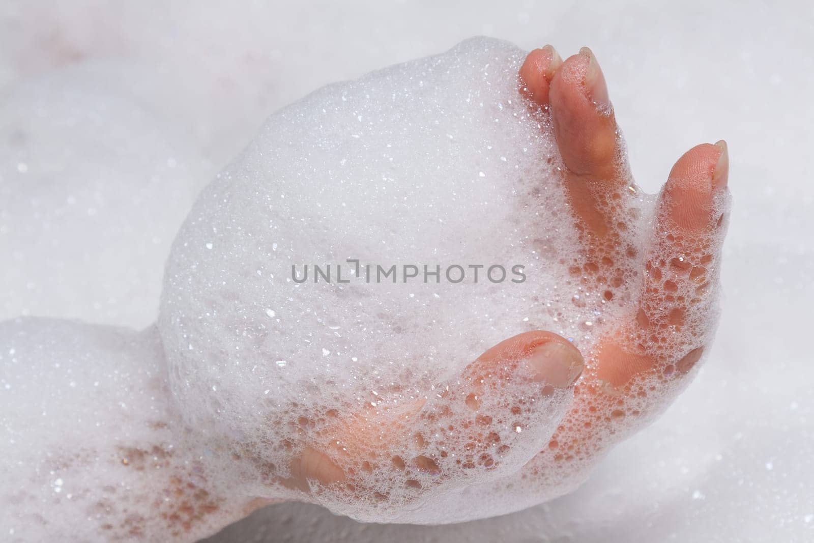 woman's hand in the foam in the bathtub