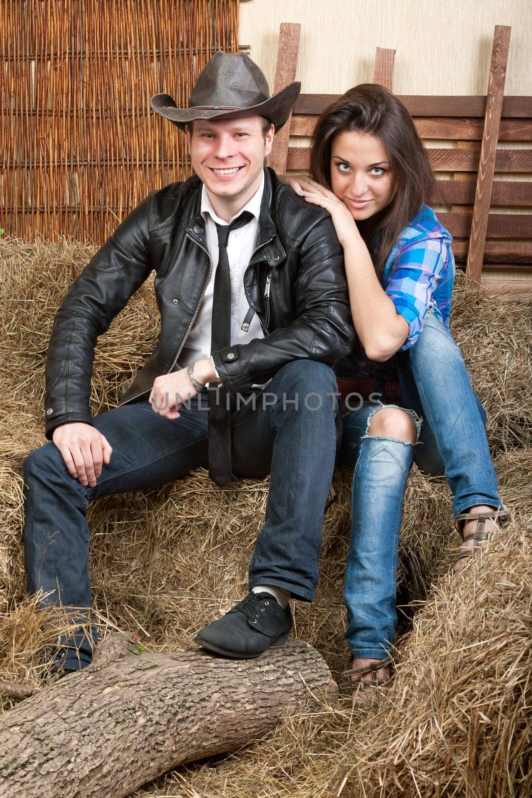 A young cowboy with sexual girl sitting on the hay