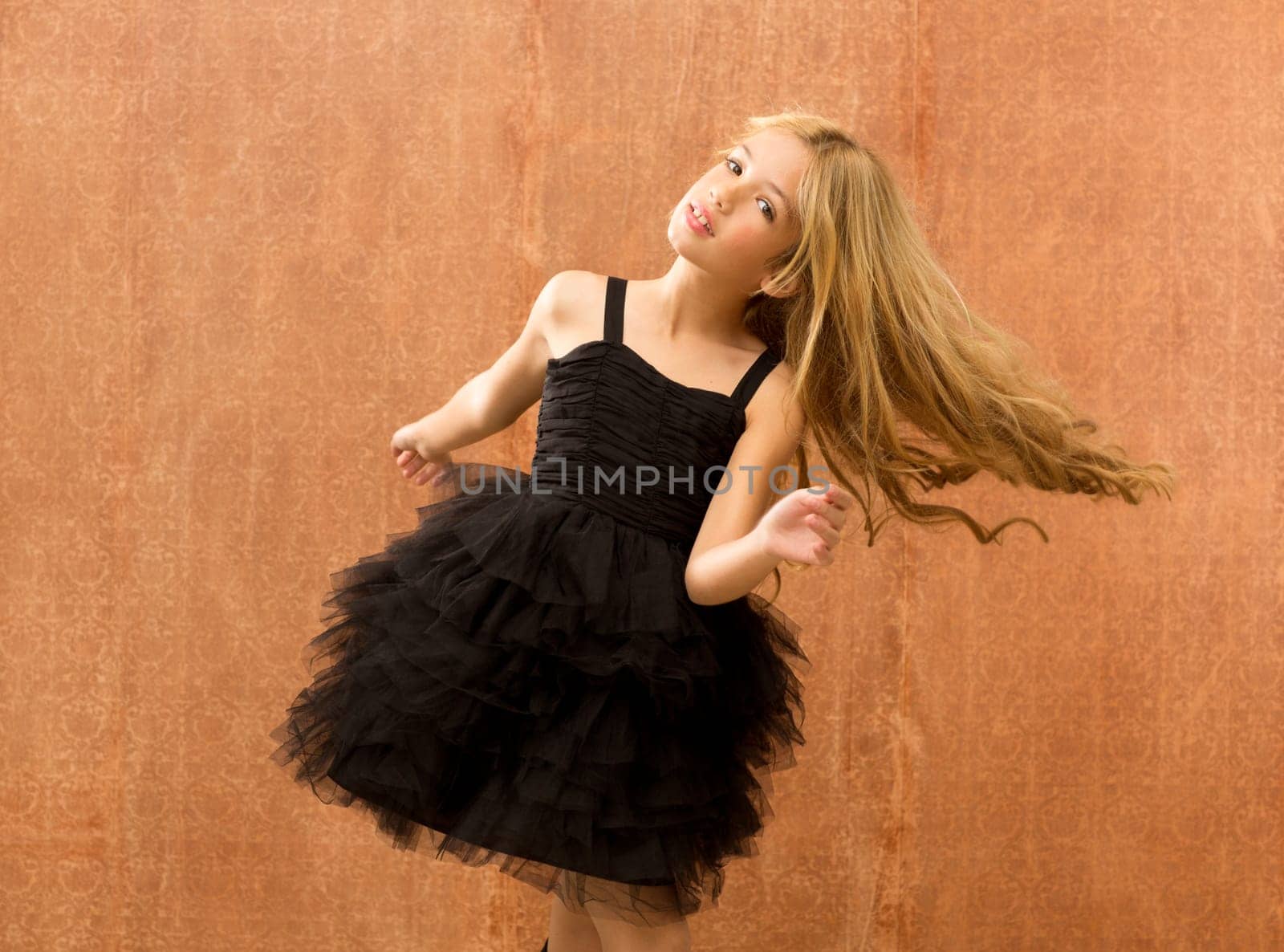 black dress kid girl dancing and twisting on vintage background