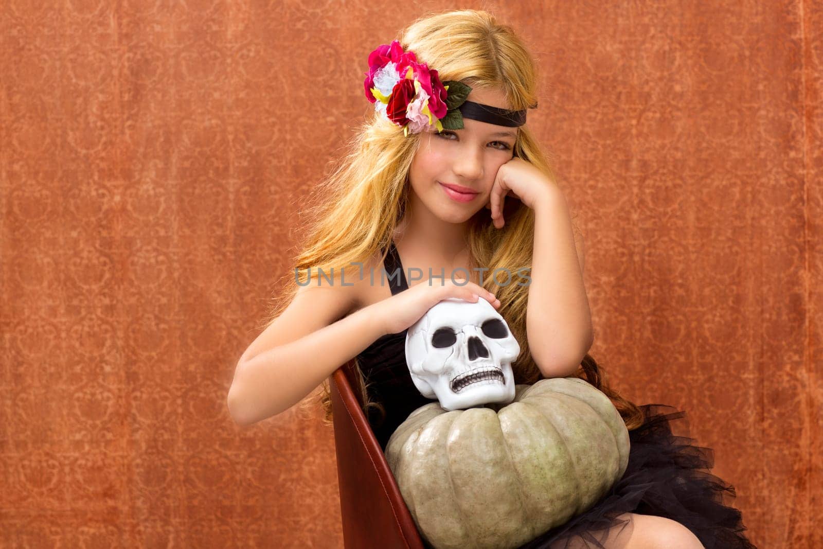 halloween kid girl with pumpkin and skull smiling on vintage background