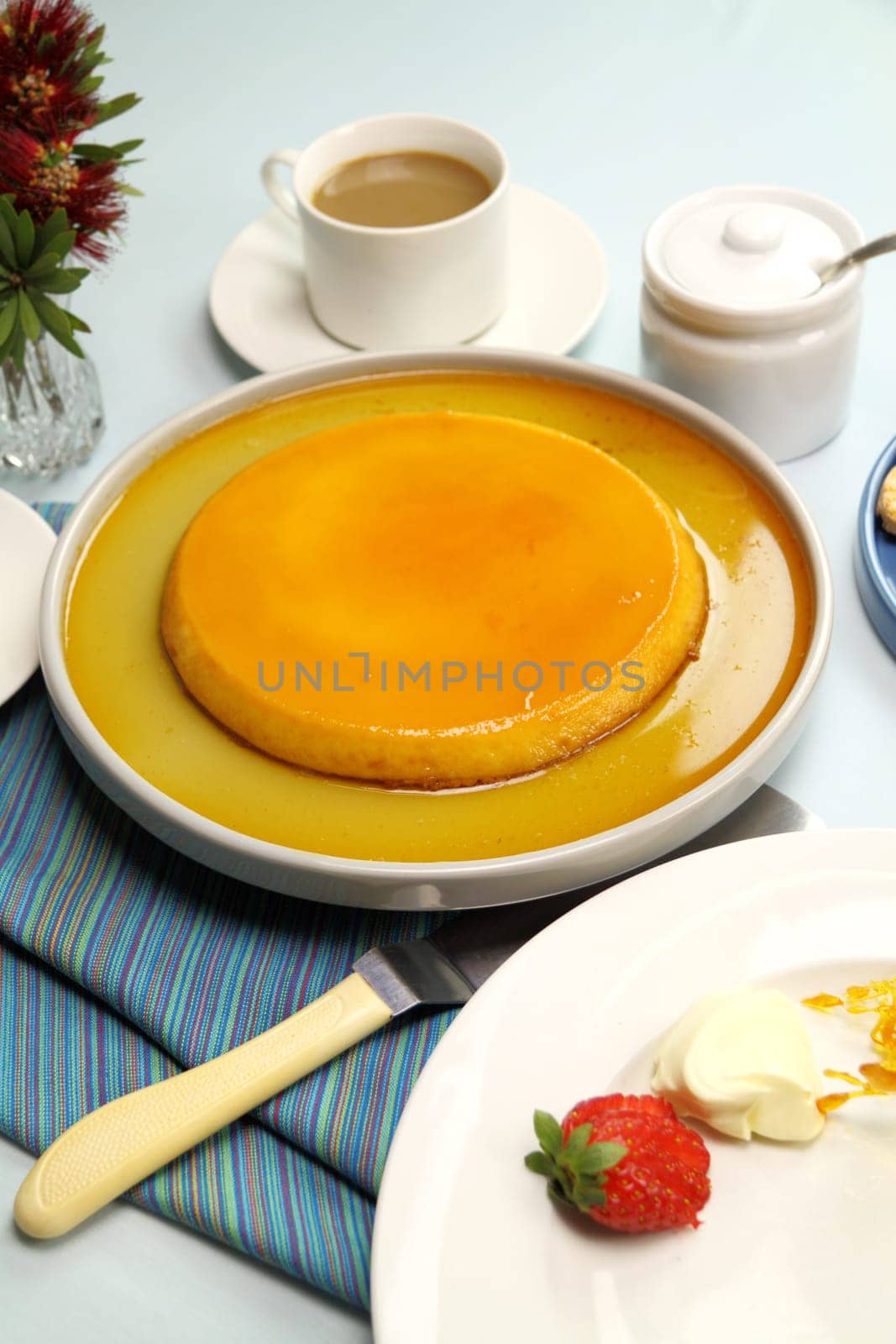 Creme caramel dessert ready to be served with coffee, strawberries and cream.