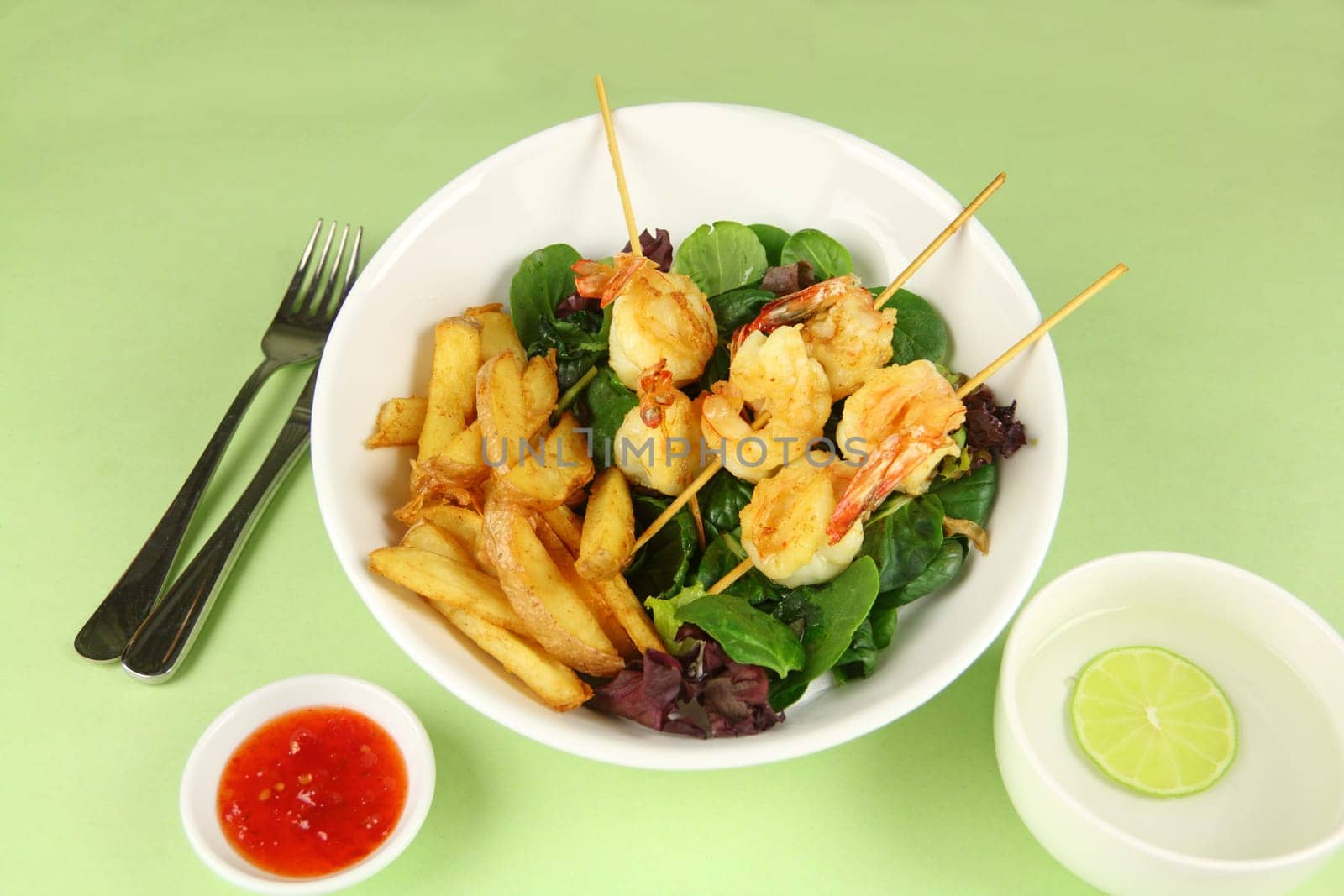 Yummy fried shrimp skewers with chunky chips with sweet chilli sauce ready to serve.
