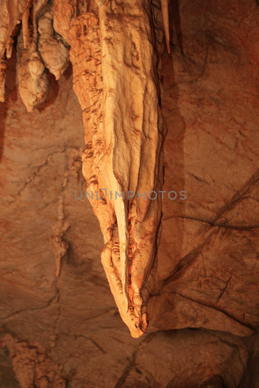 A large stalactite hanging from the roof of a cave.