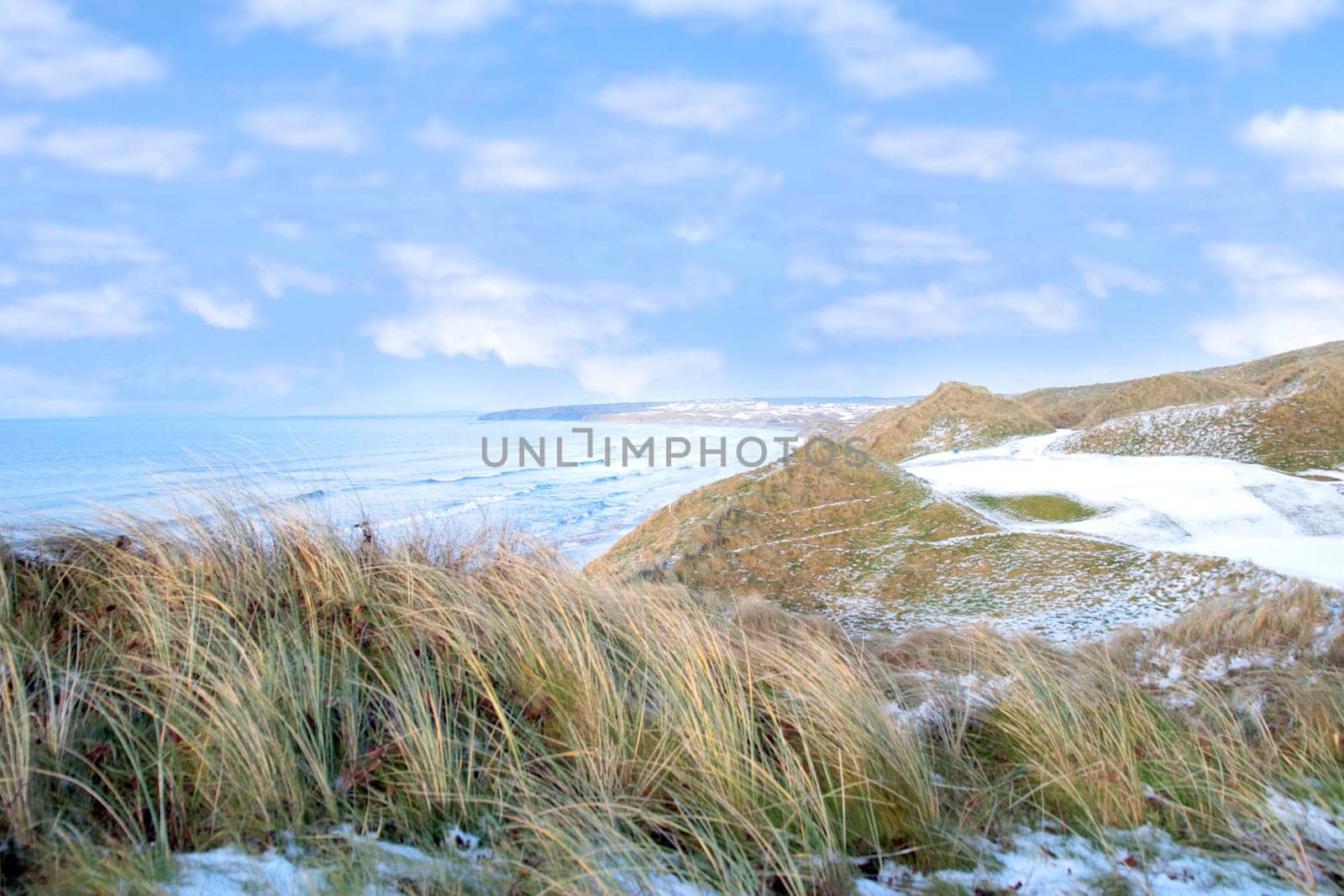 atlantic ocean beside a snow covered links golf course in ireland in snowy winter weather