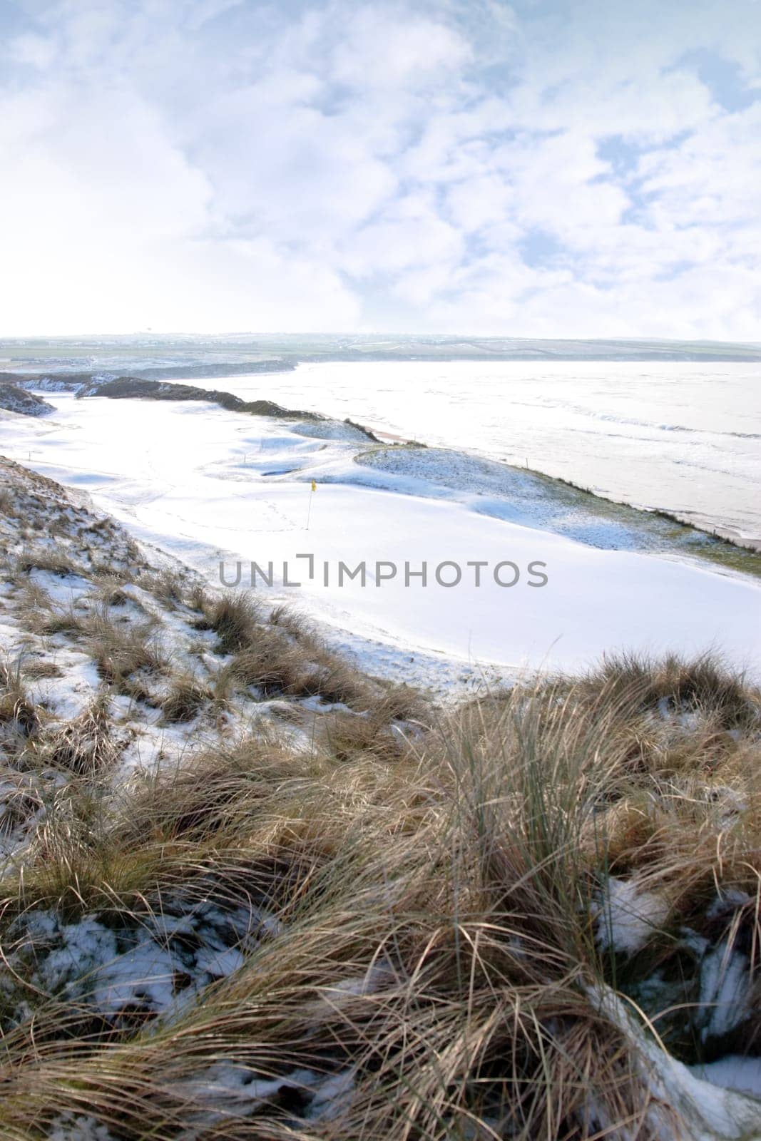 atlantic ocean beside a snow covered links golf course in ireland in snowy winter weather