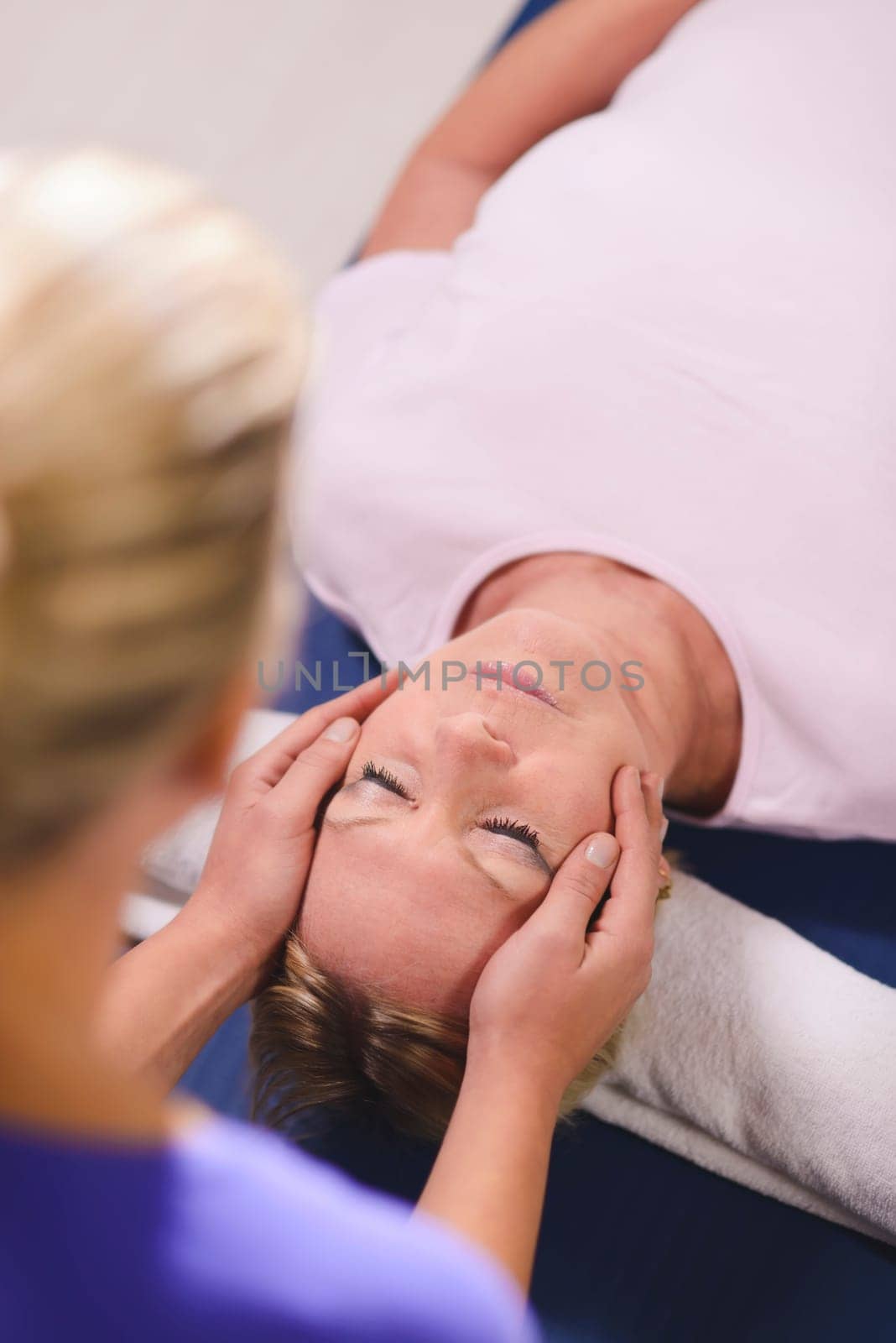 Alternative traditional medicine and massage, young spirit healer doing reiki treatment to old woman. Head and shoulders