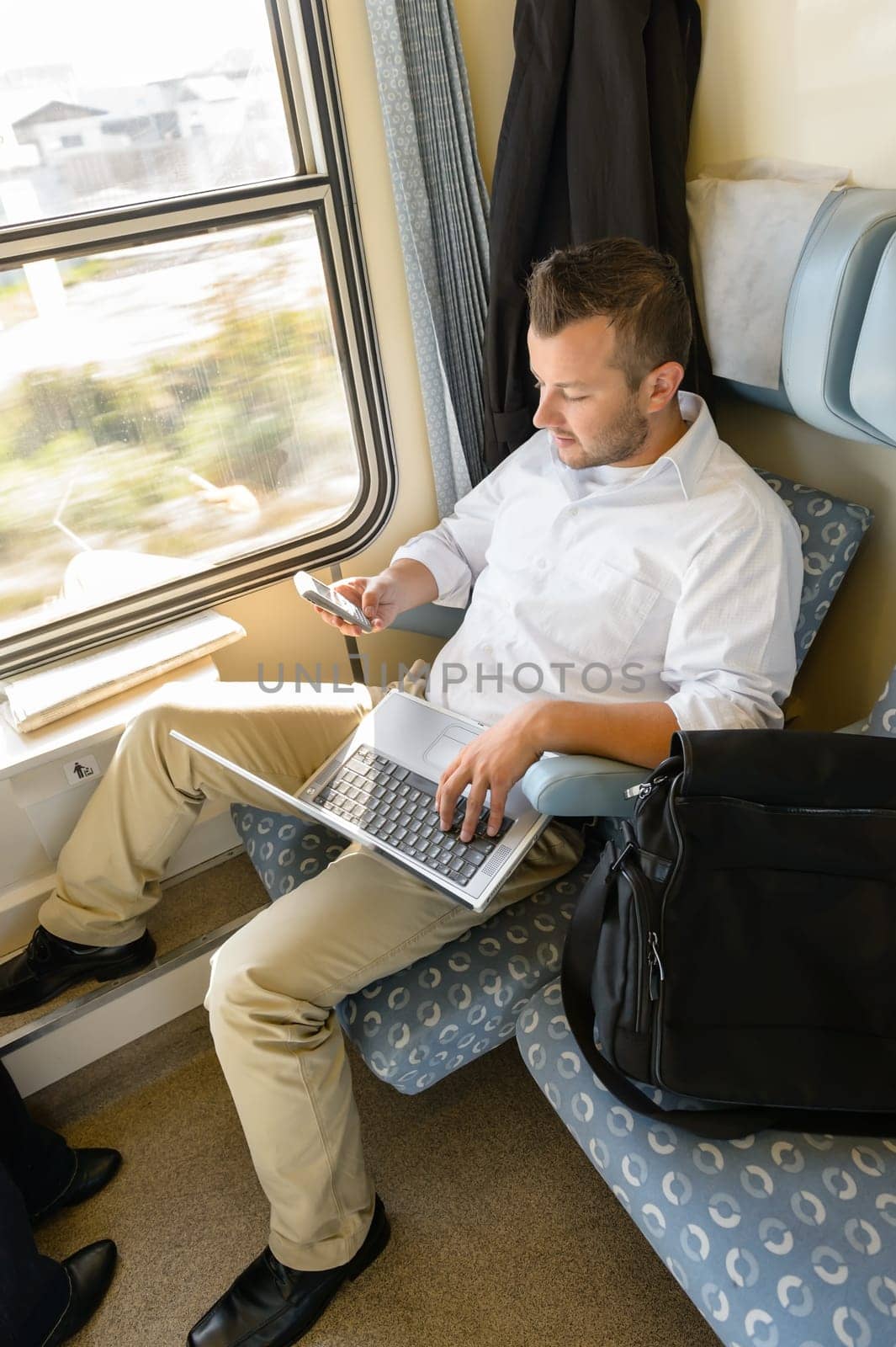 Man texting on phone holding laptop train commuter work journey