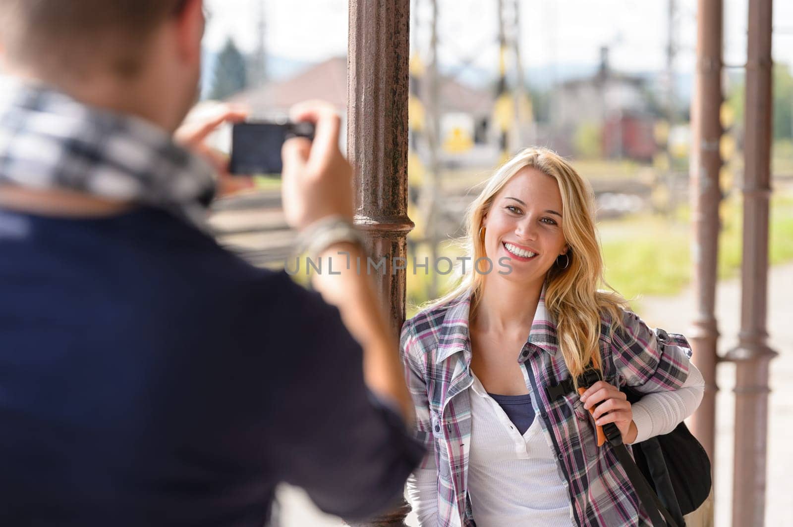 Woman smiling man taking her picture vacation backpack railroad camera