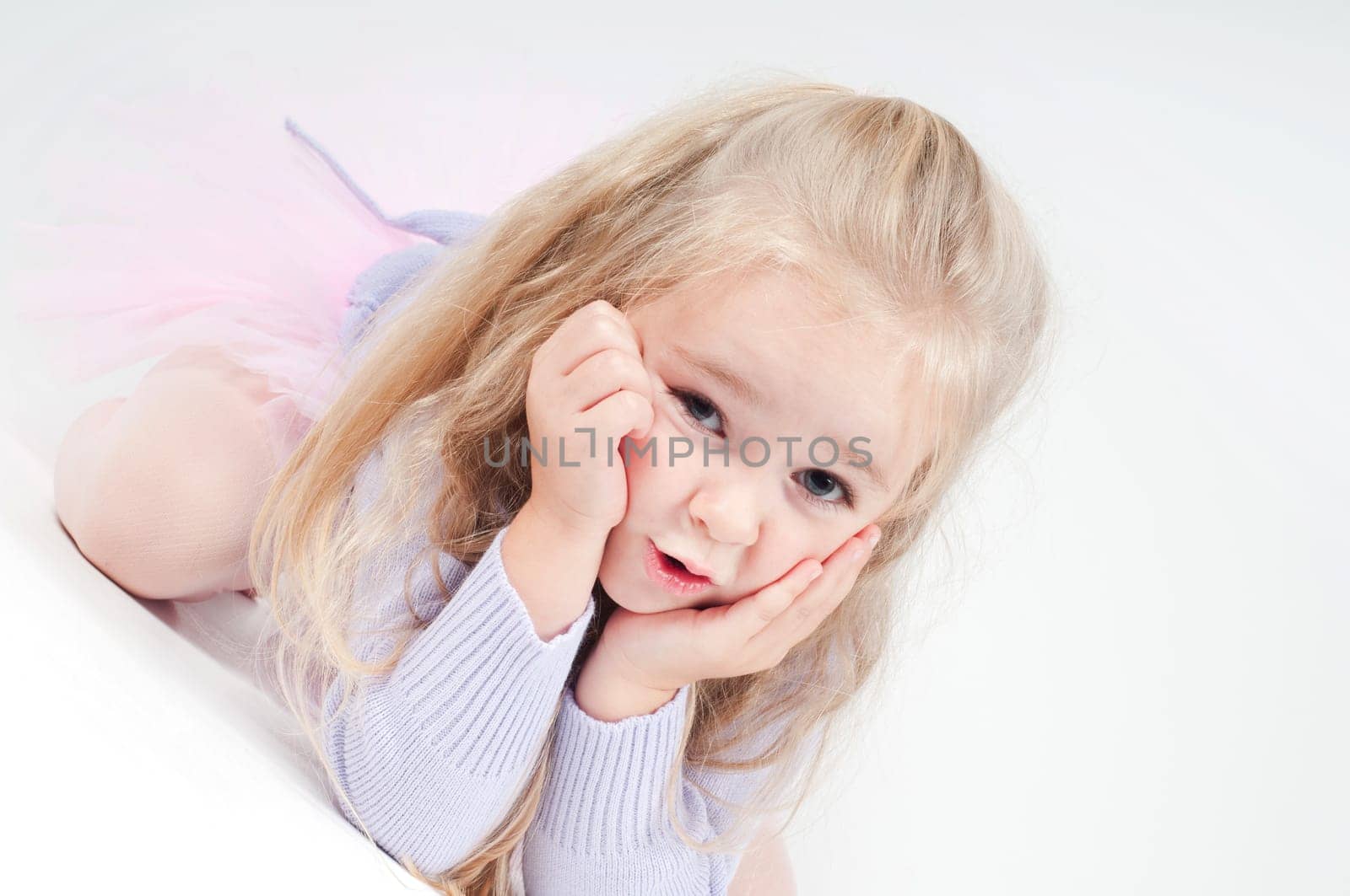 Cute blond girl sitting on the floor and watching on you