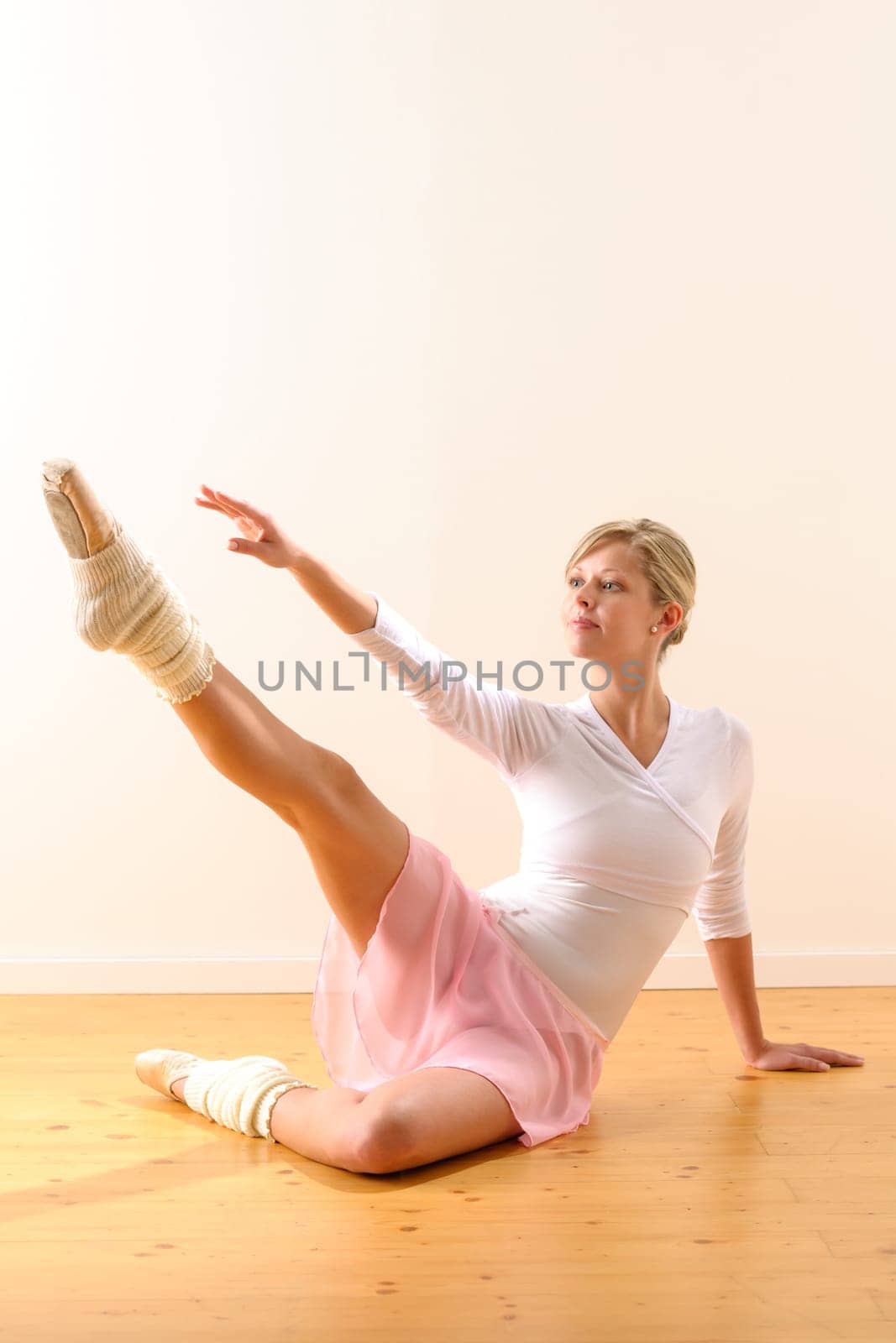 Beautiful ballet dancer lifting arm towards leg exercise woman ballerina