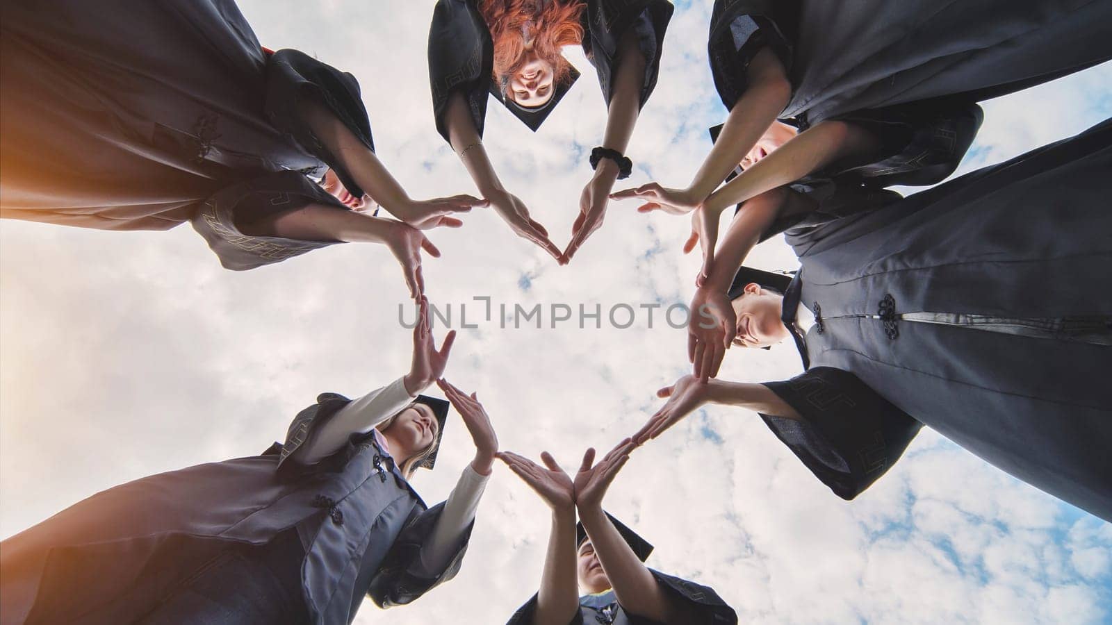 Students graduating from the college make a heart out of their hands