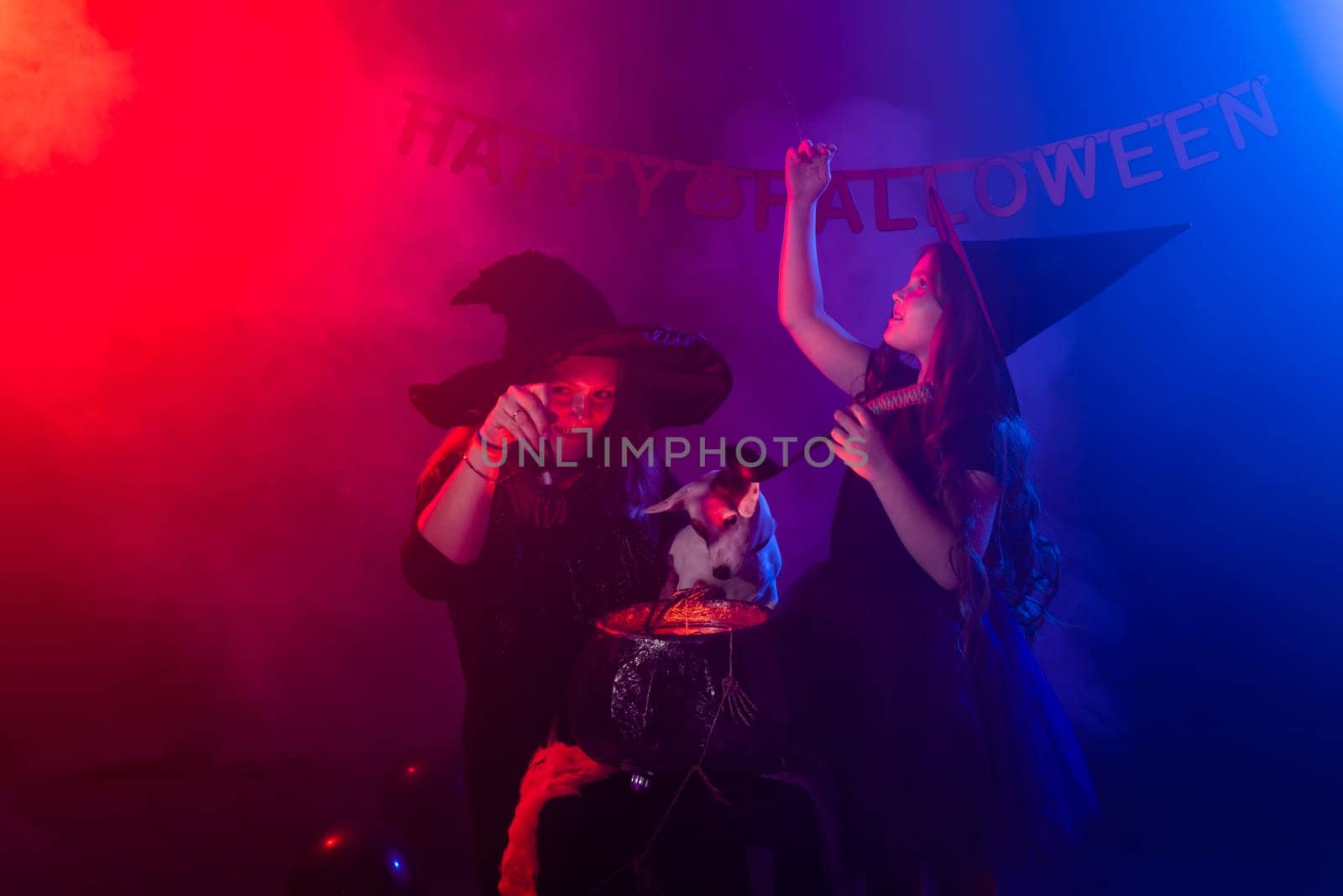 Funny child girl and woman in witches costumes for Halloween with pumpkin Jack and dog