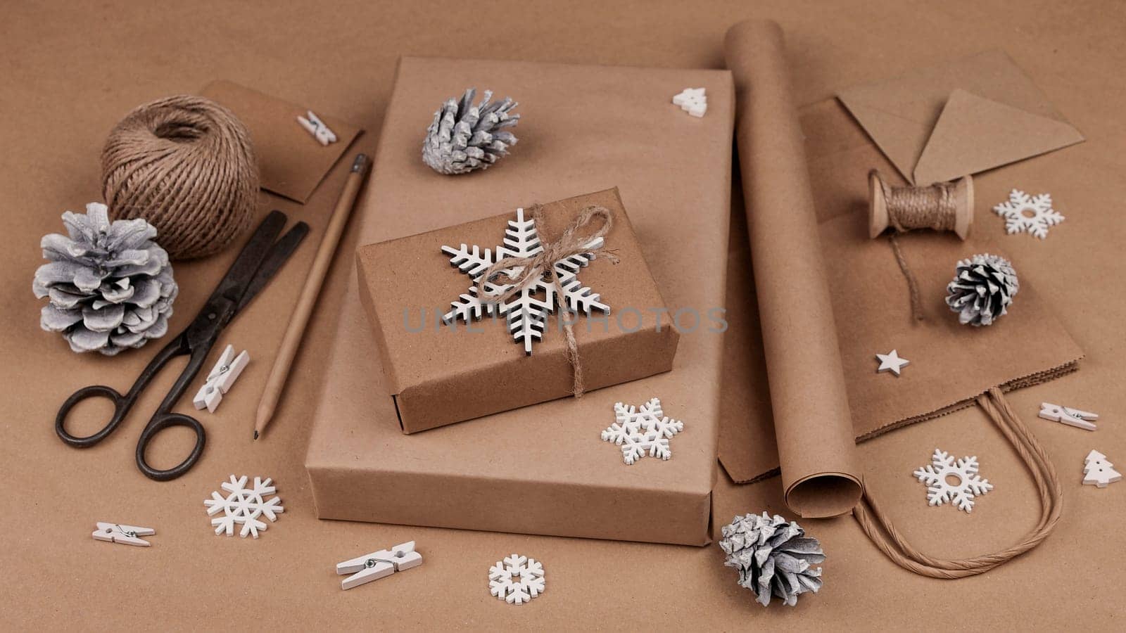 Close up packing and wrapping Christmas gift boxes in natural brown paper, high angle view