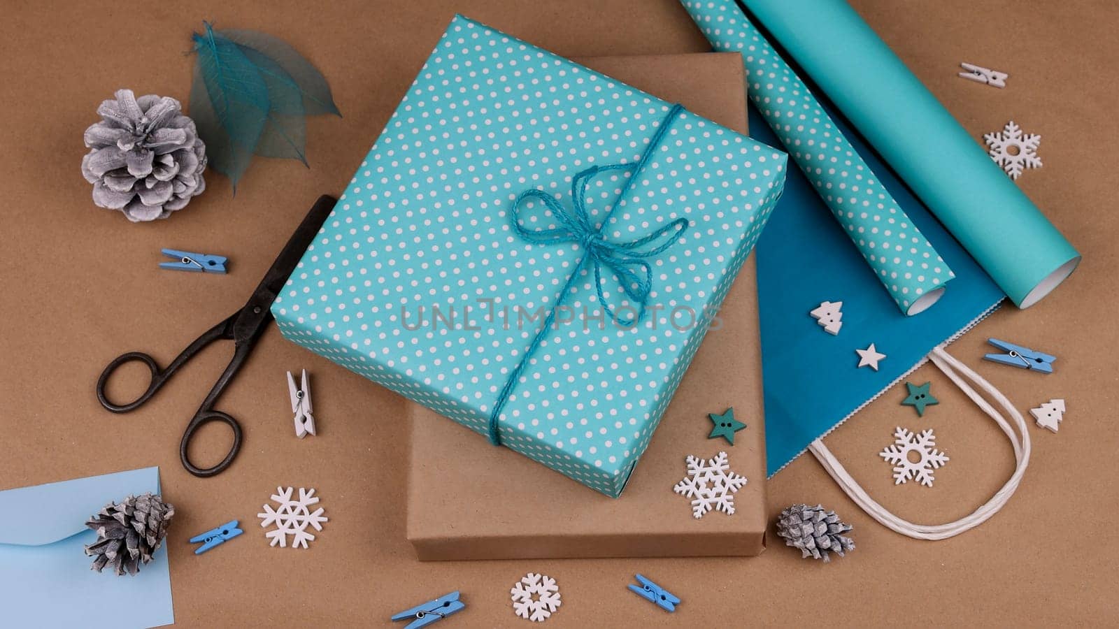 Close up packing and wrapping Christmas gift boxes with blue paper, high angle view