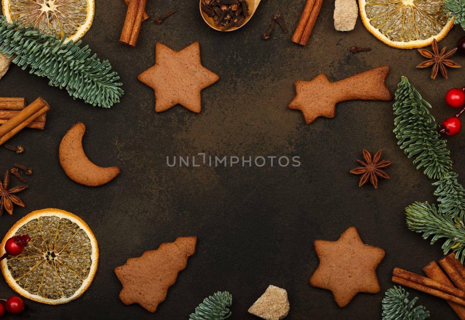 Making sweet gingerbread cookies on table with Christmas decorations and cooking ingredients over dark brown background with copy space, close up, table top view, directly above