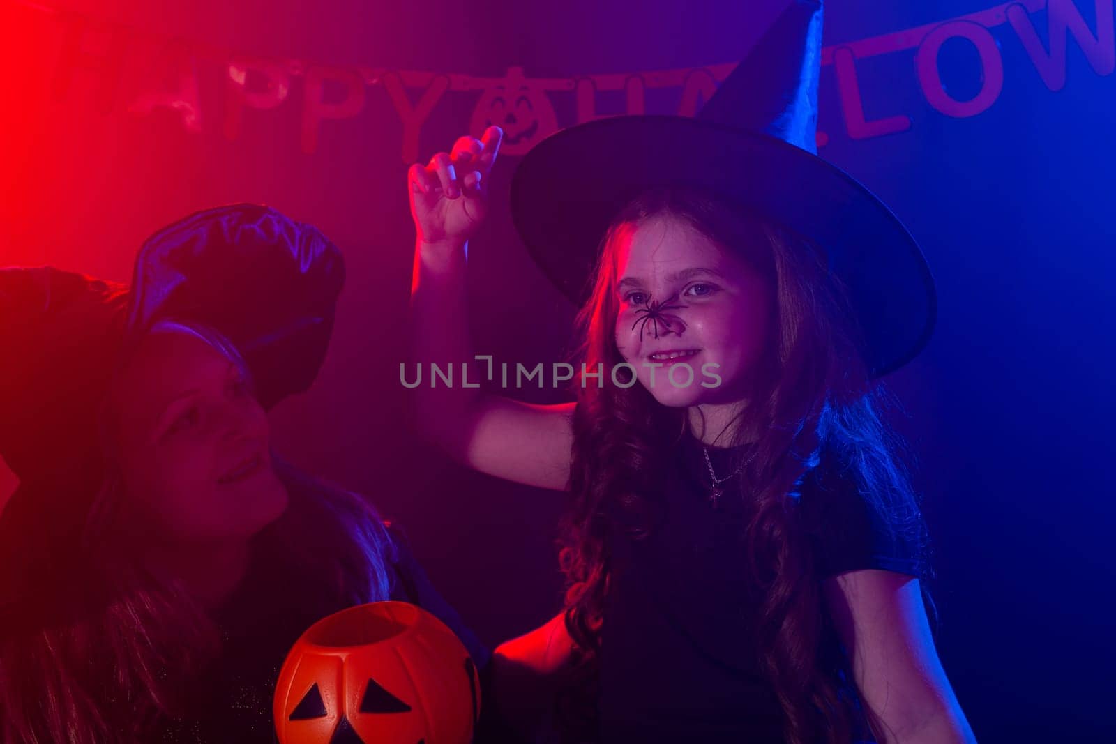 Funny child girl in witch costume for Halloween with spider