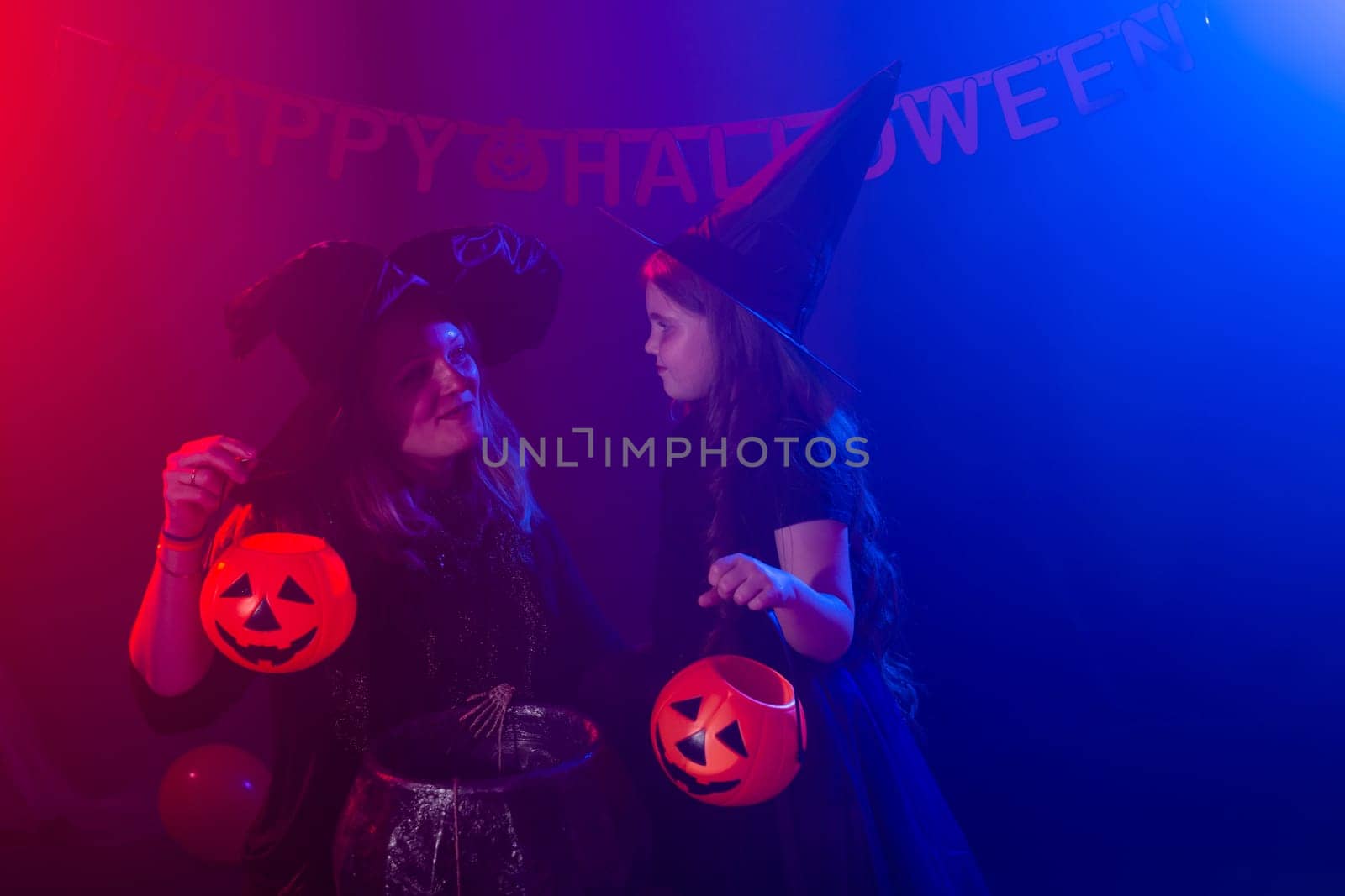 Funny child girl and woman in witches costumes for Halloween with pumpkin Jack and dog