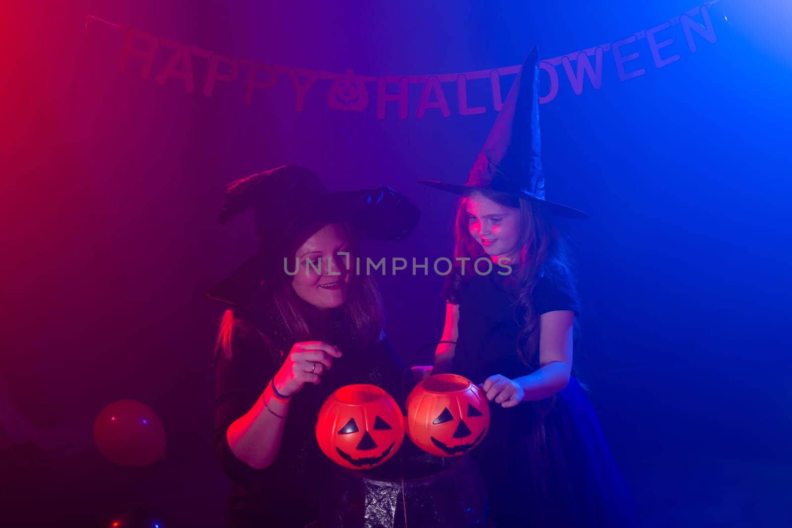 Funny child girl and woman in witches costumes for Halloween with pumpkin Jack and dog