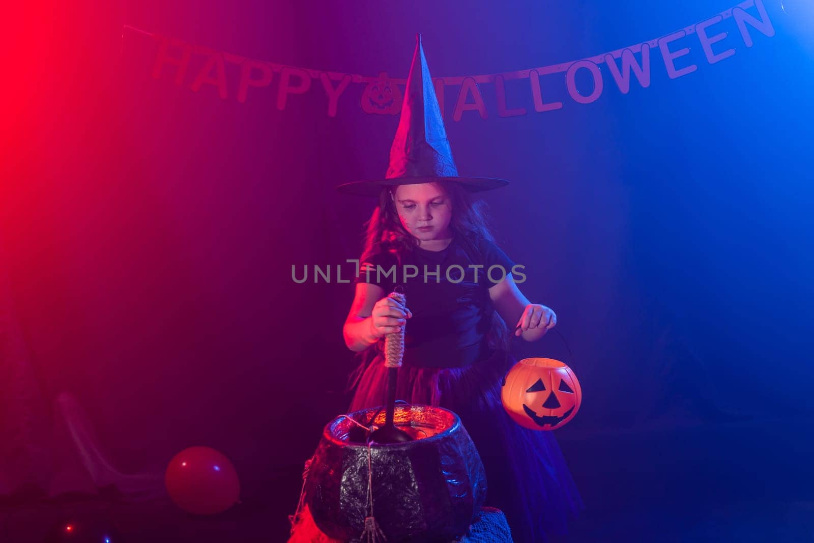 Little witch child cooking potion in the cauldron on Halloween