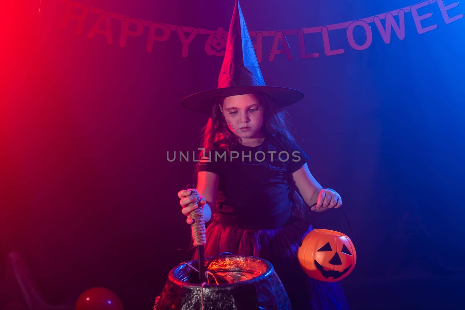 Little witch child cooking potion in the cauldron on Halloween