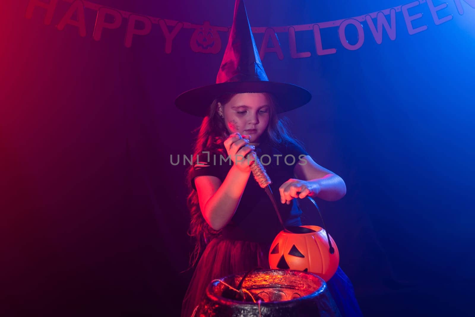 Little witch child cooking potion in the cauldron on Halloween