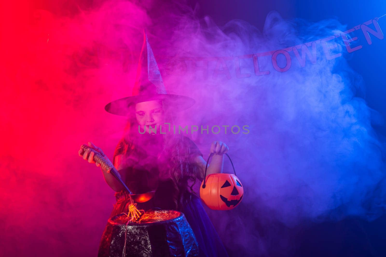 Little witch child cooking potion in the cauldron on Halloween