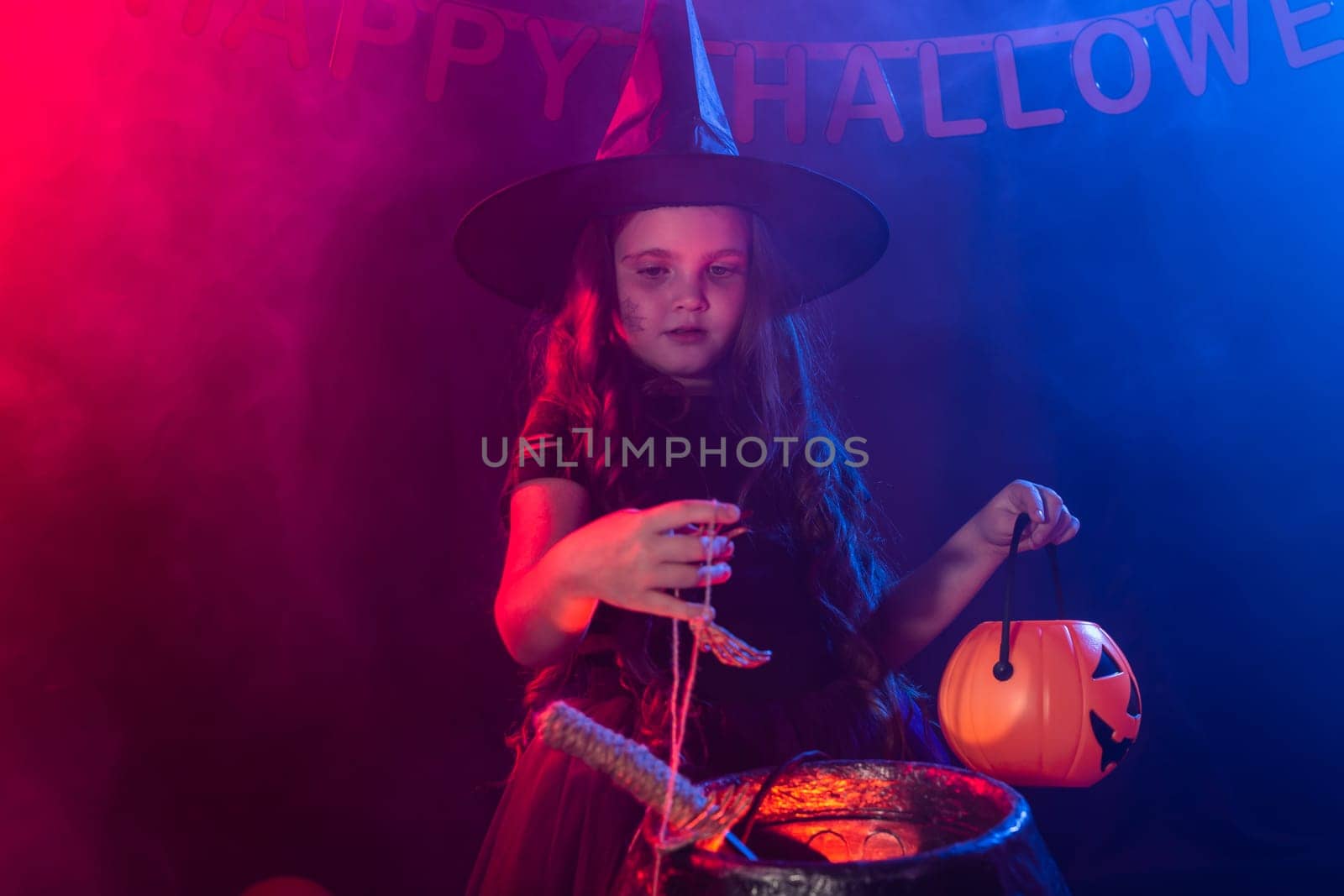 Little witch child cooking potion in the cauldron on Halloween