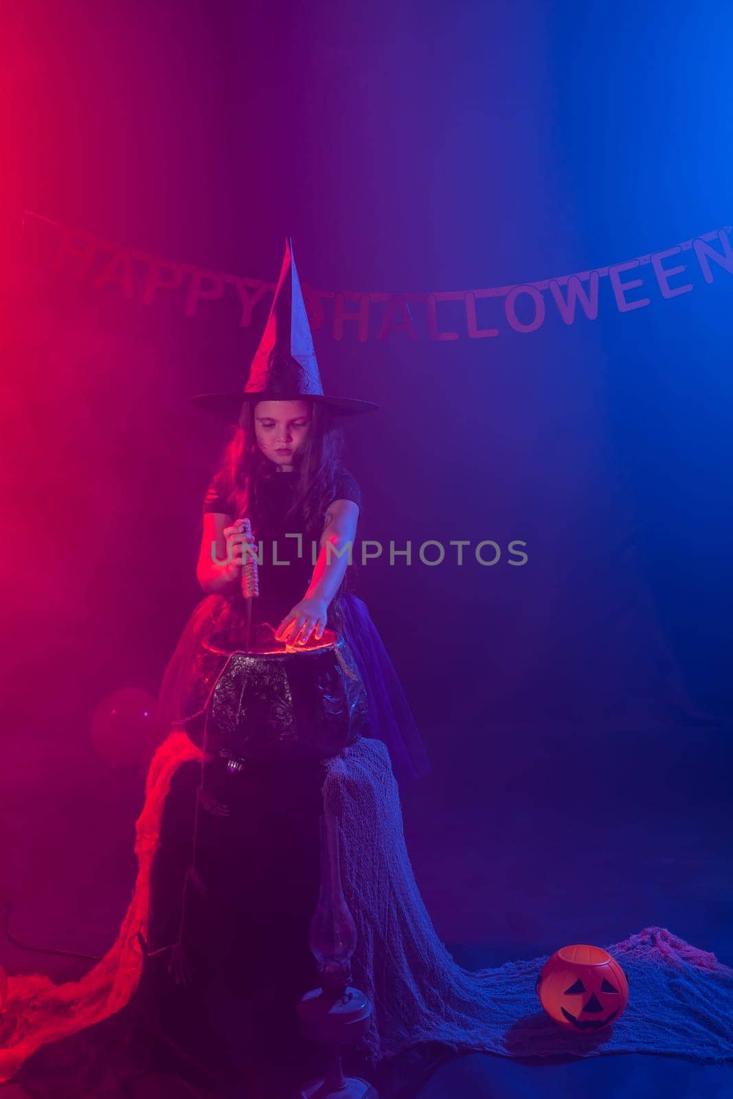 Little witch child cooking potion in the cauldron on Halloween