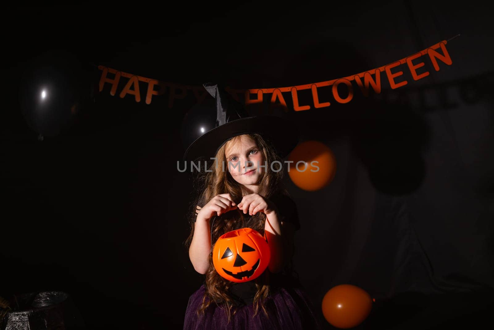 Funny child girl in witch costume for Halloween with pumpkin Jack