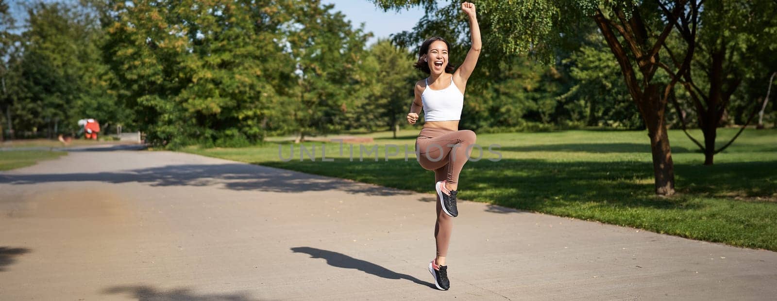 Hooray, victory. Smiling asian girl triumphing, celebrating achievement, running till finish, shouting from excitement.