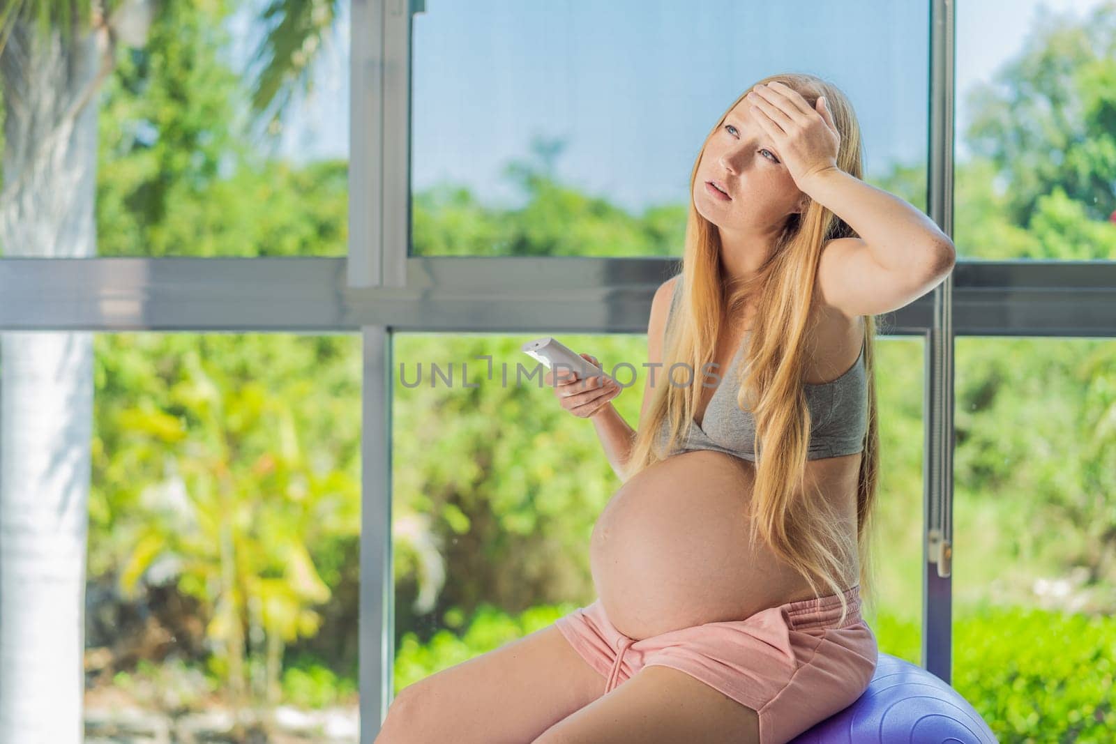 In the midst of a hot day, a pregnant woman finds relief and comfort as she enjoys the cooling embrace of air conditioning, ensuring a soothing and relaxing atmosphere by galitskaya