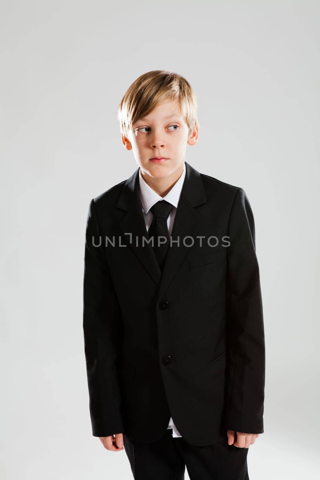 Studio portrait of serious looking young boy wearing black suit