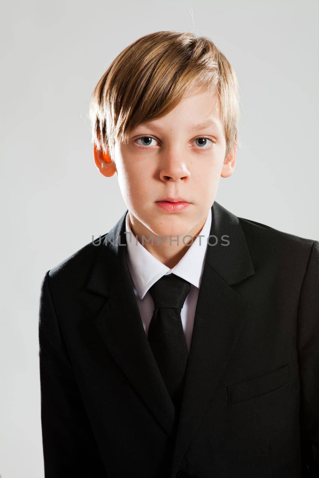 Studio portrait of serious looking young boy wearing black suit