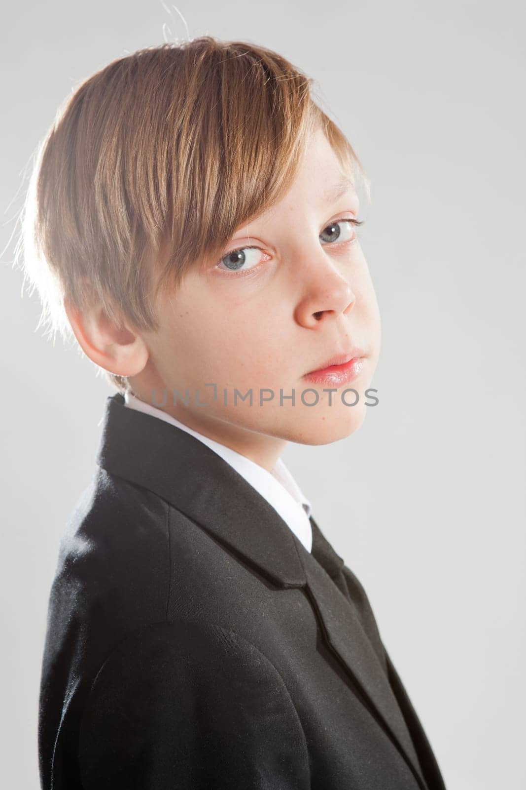 Studio portrait of serious looking young boy wearing black suit
