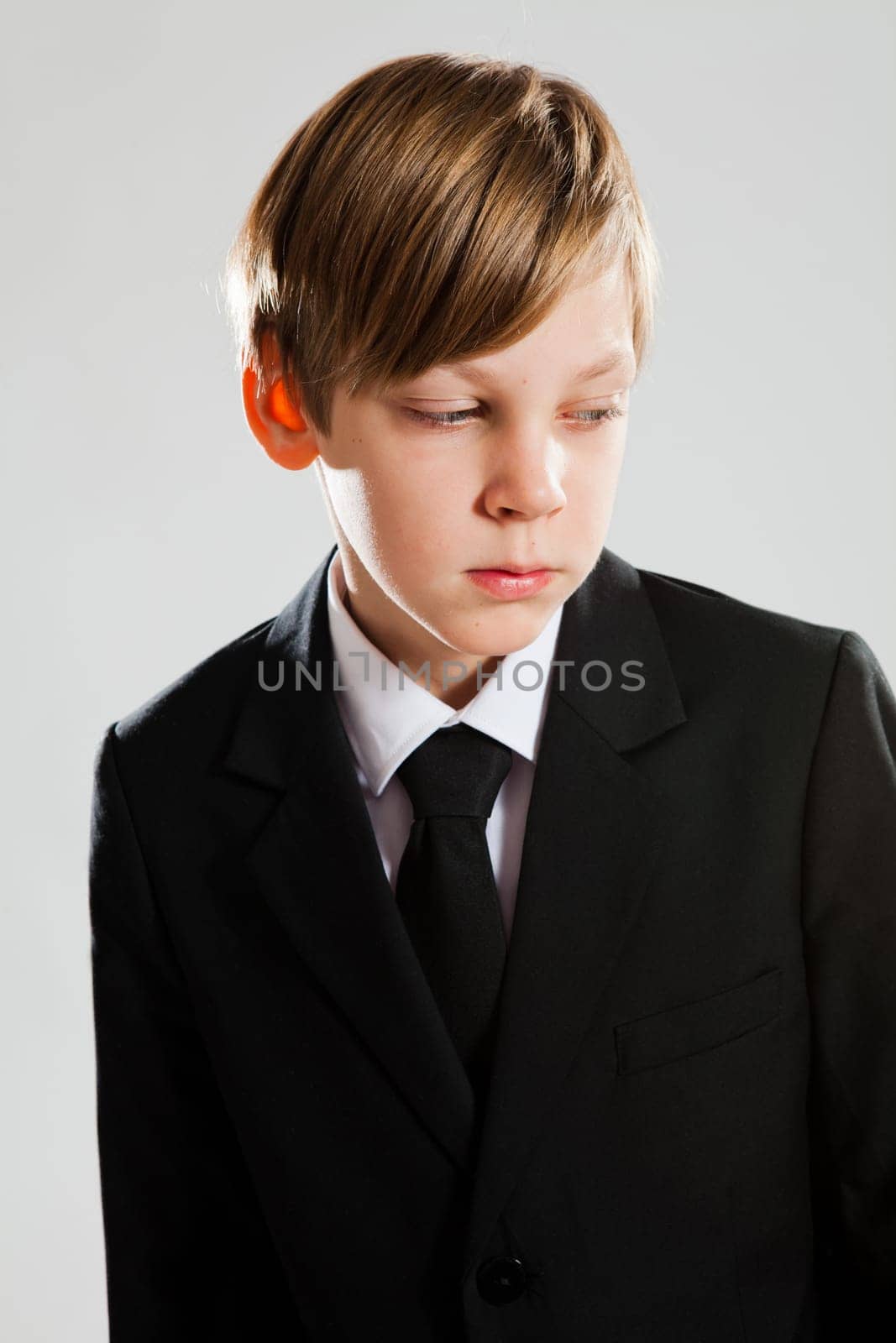 Studio portrait of serious looking young boy wearing black suit