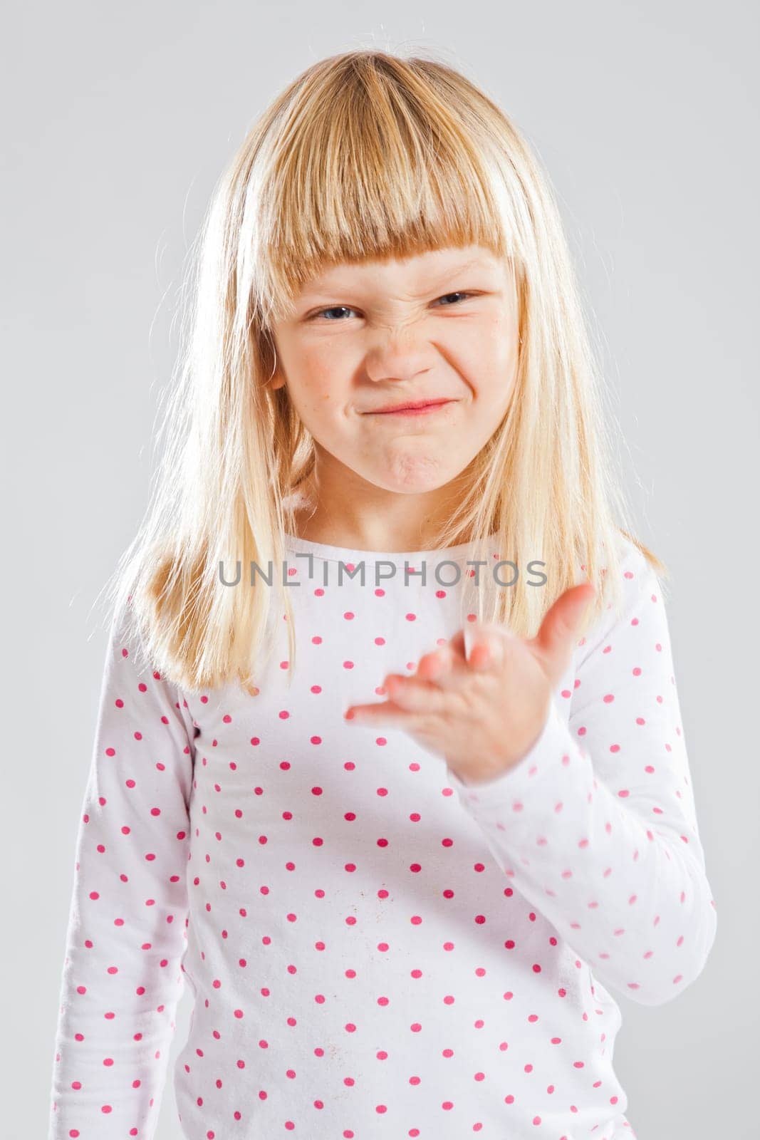 Studio portrait of young girl showing funny grin and hand gesture