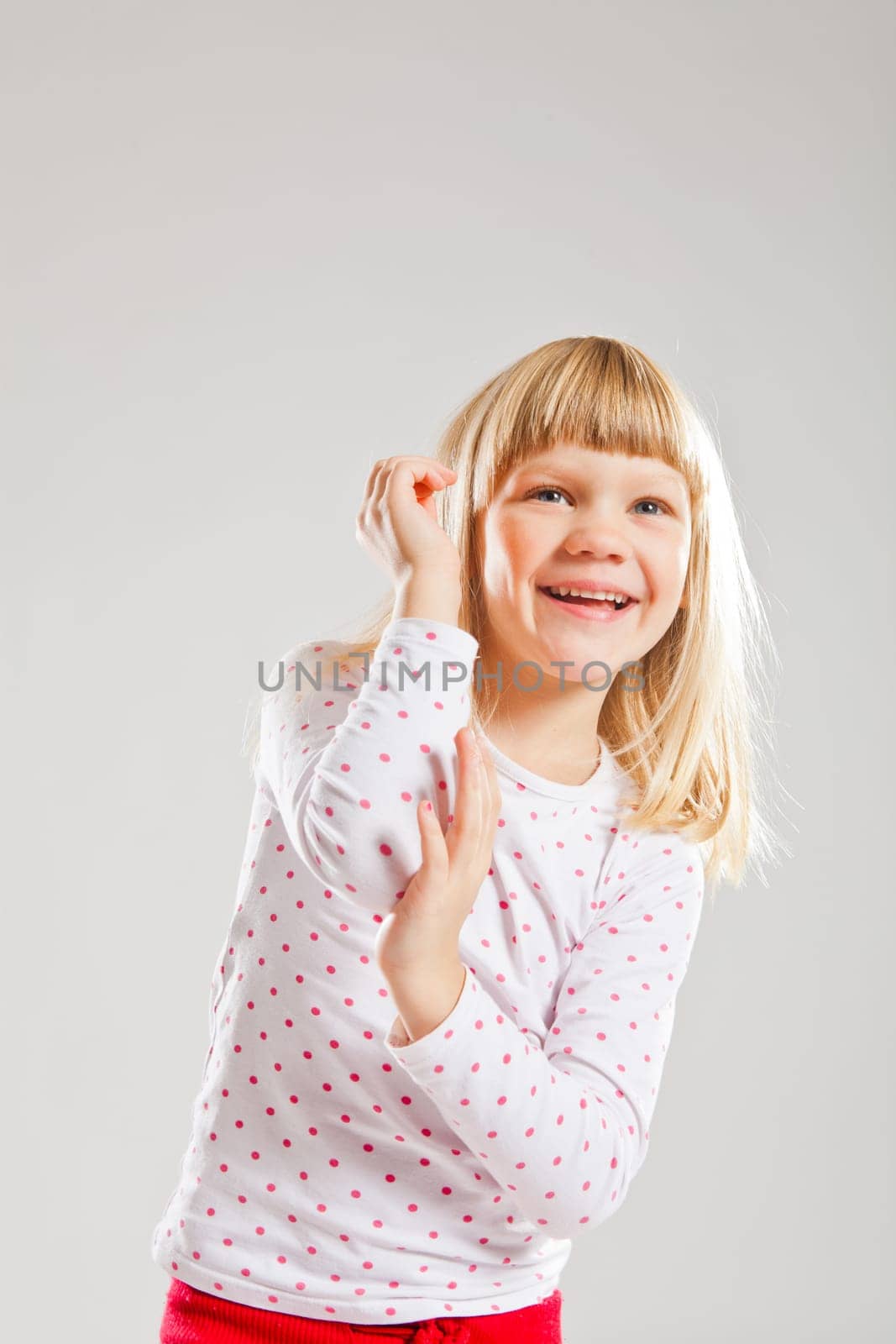 Studio portrait of happy smiling young girl looking upwards with raised hands