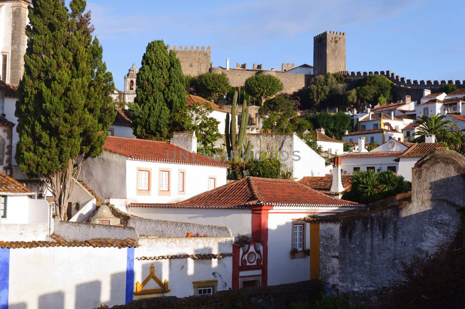 Medieval houses in the ancient city of Obidos, Portugal with castle walls  in the background