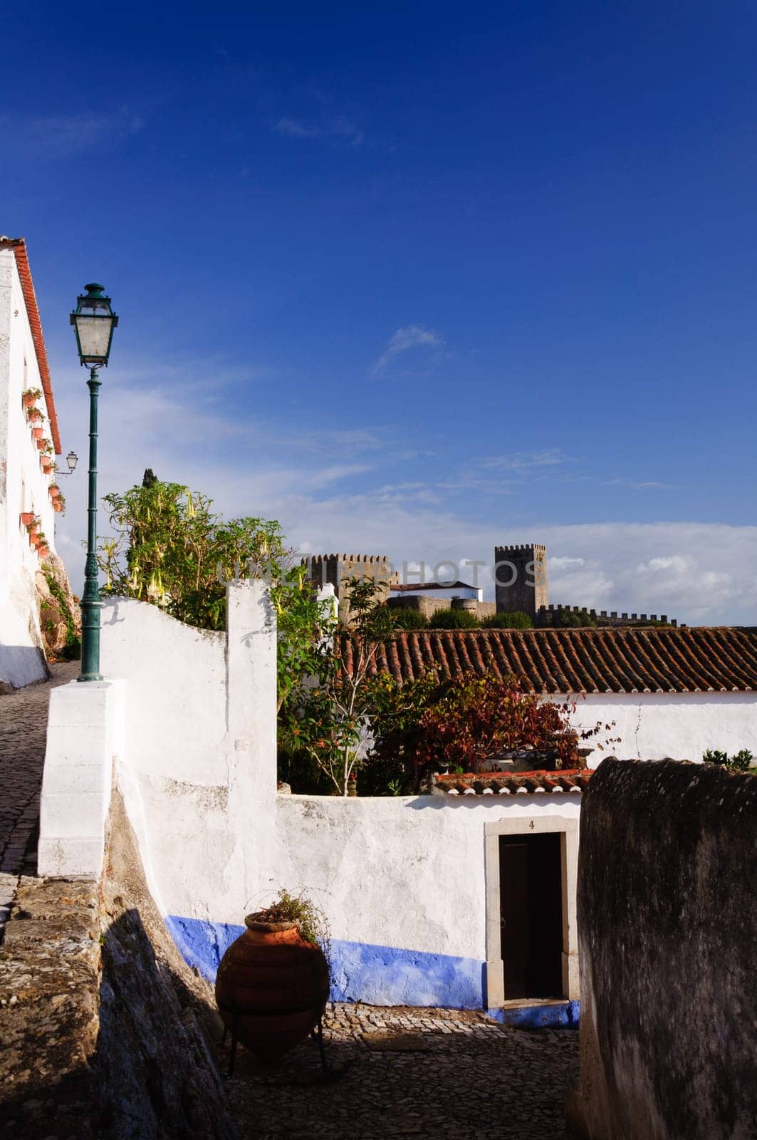 Medieval houses in the ancient city of Obidos, Portugal with castle walls  in the background