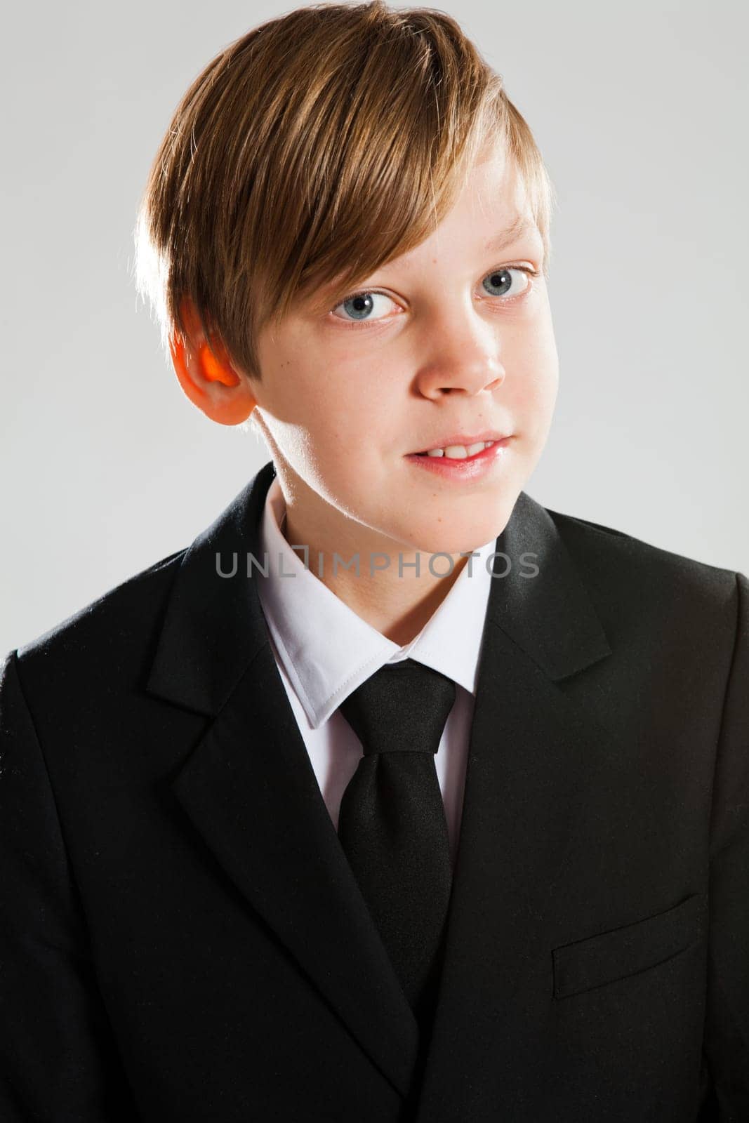 Studio portrait of a happy smiling young boy wearing black suit