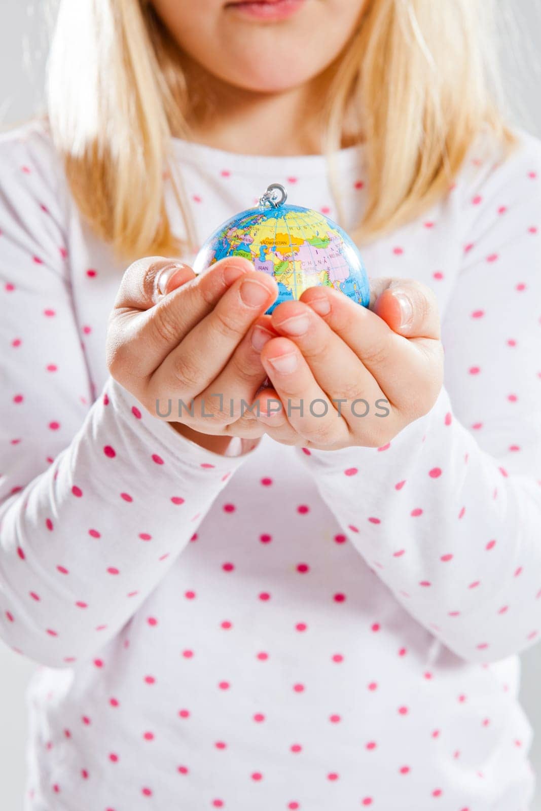 Studio portrait of young girl holding world globe in hands