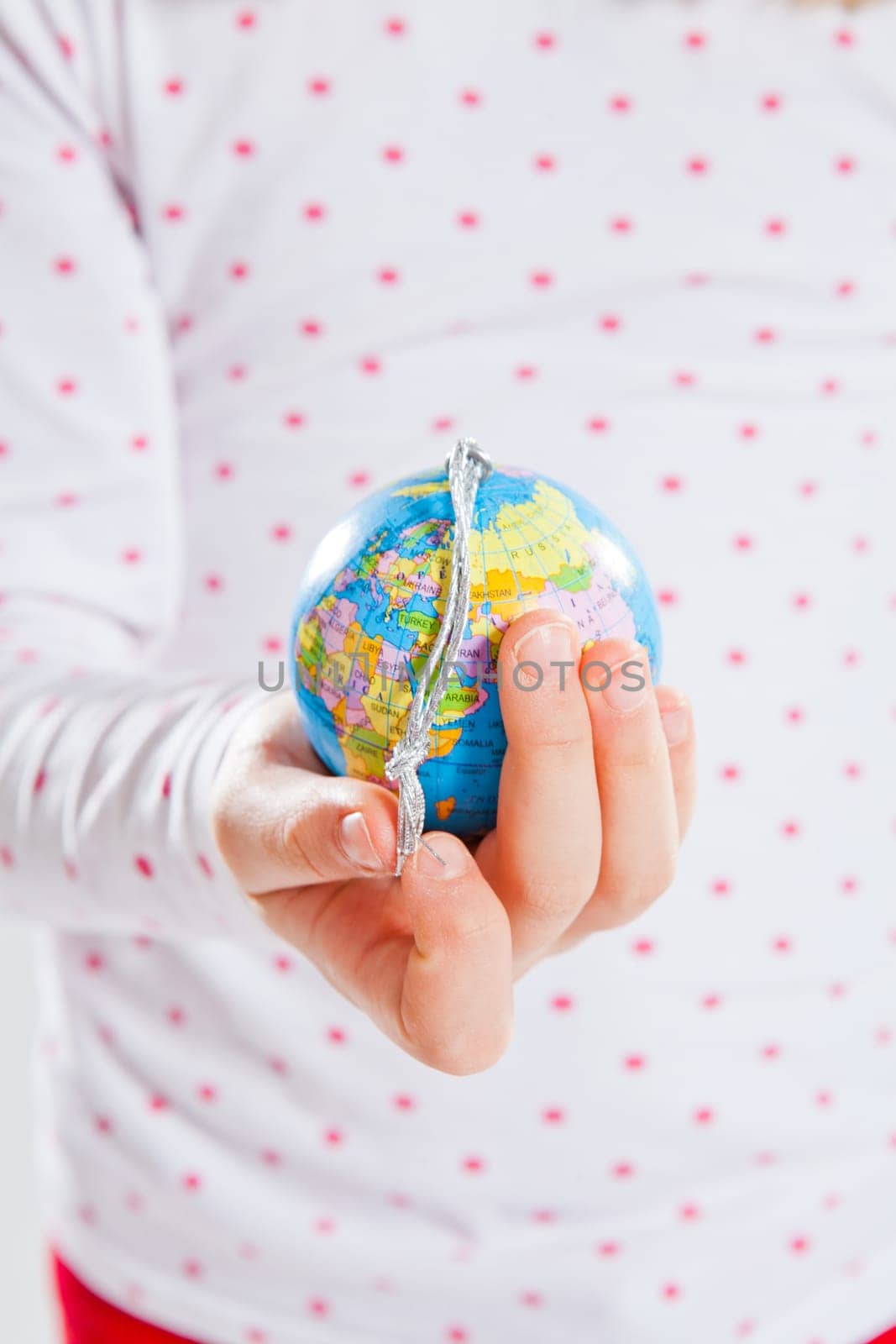Studio portrait of young girl holding world globe in hand
