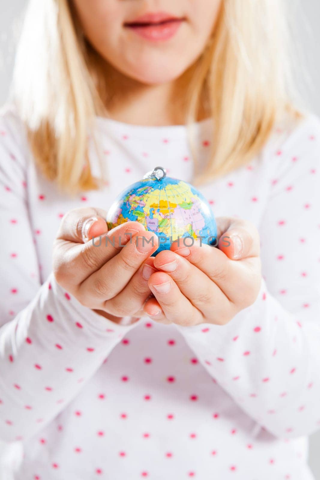 Studio portrait of young girl holding world globe in hands