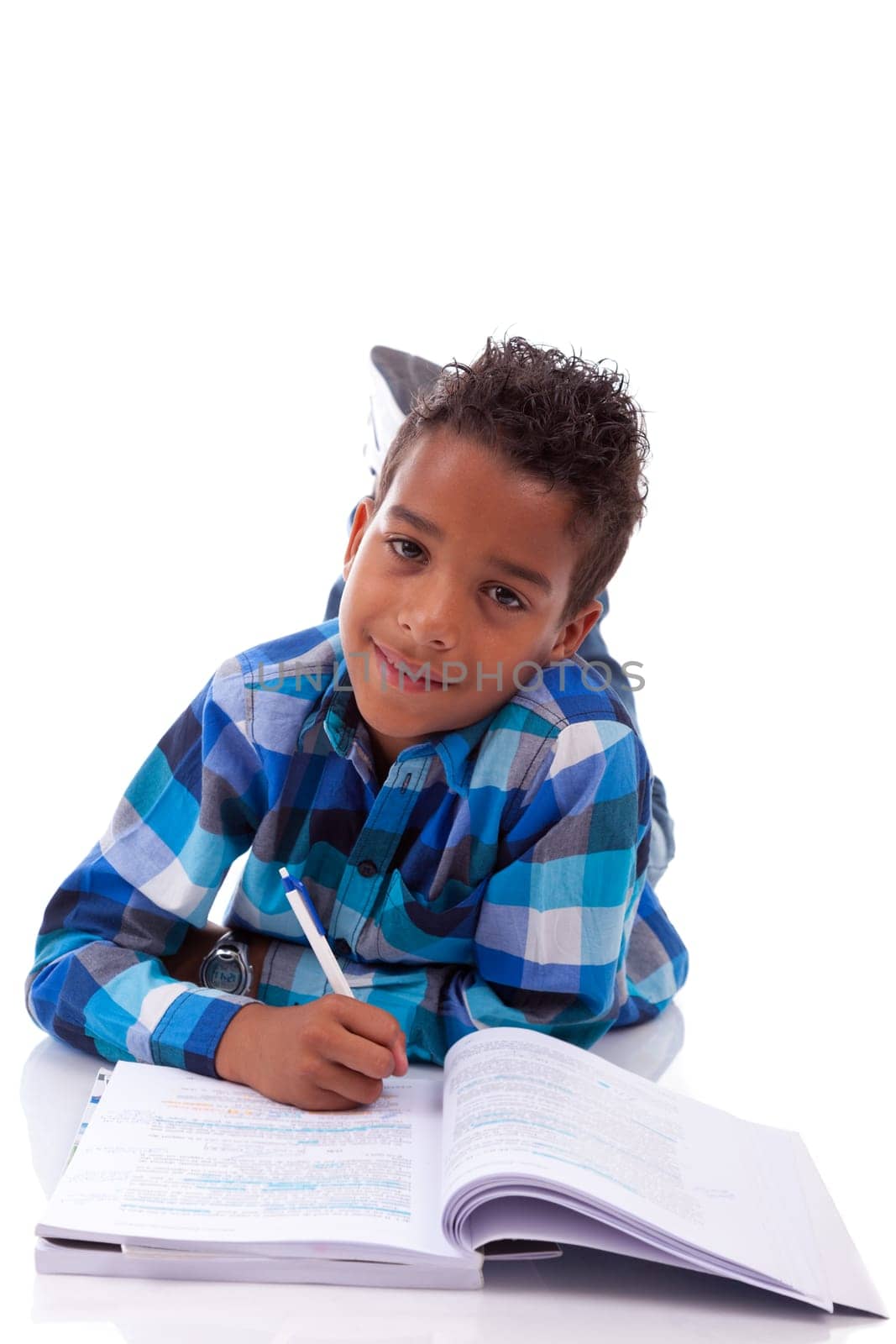 Little african boy lying down on the floor and reading book, isolated on white background