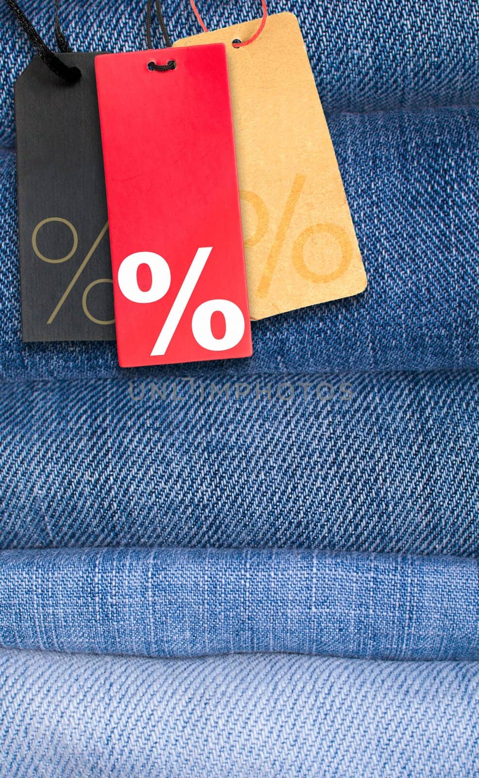 Sale Tags With Percentage Symbol on Stack of Blue Jeans