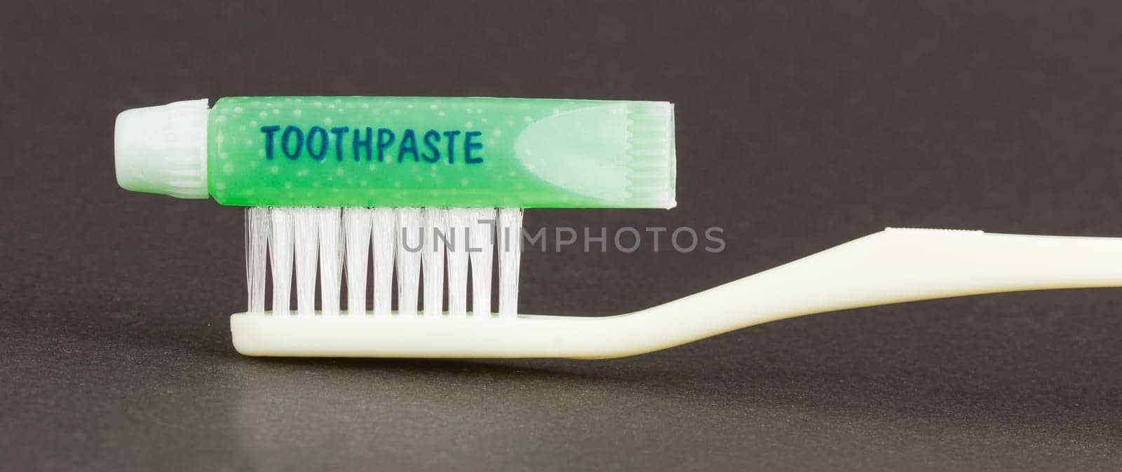 Toothbrush and green toothpaste isolated on a grey background