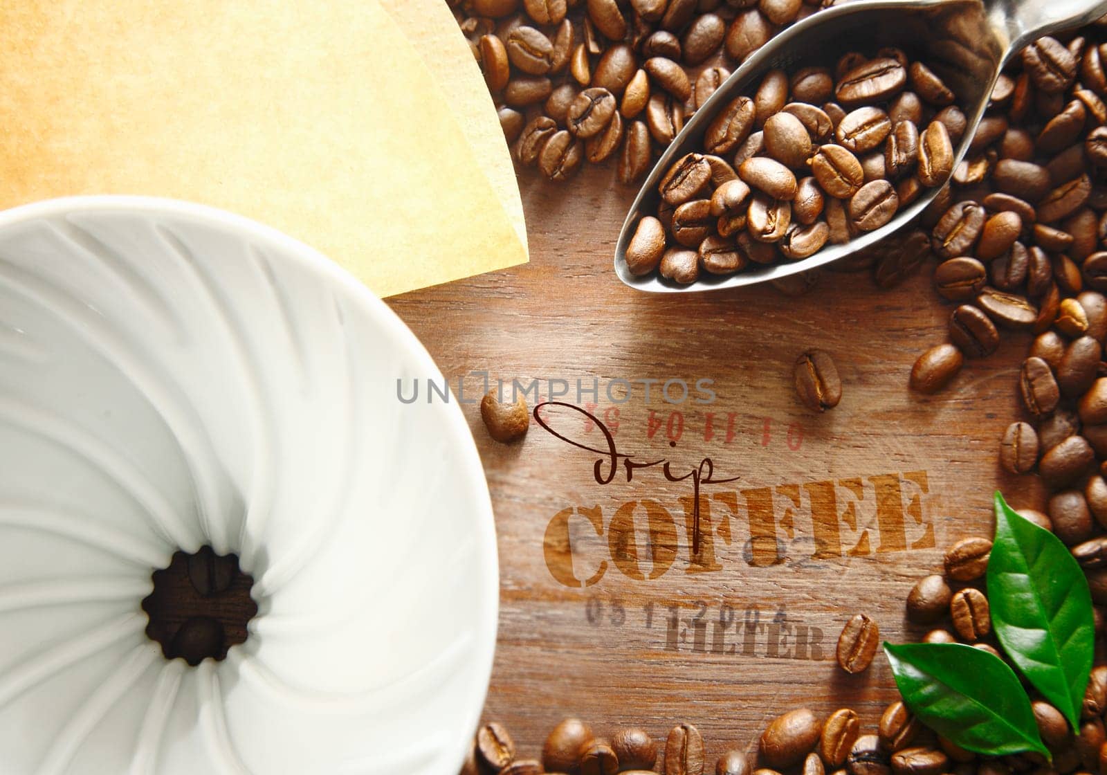 Portable plastic filter with coffee beans and a spoon surrounding the stamped text label on an old wooden coffee container for an interesting background